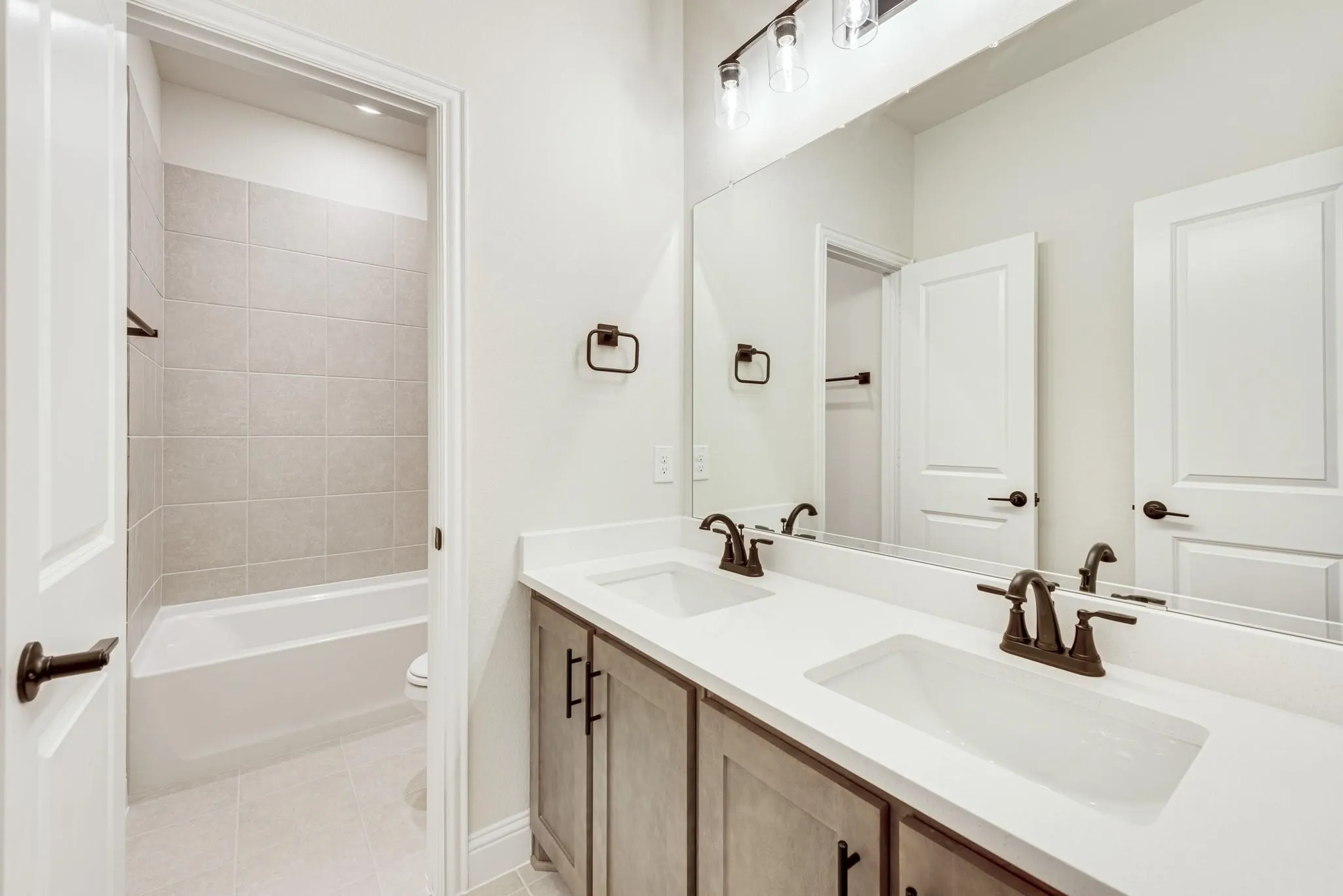 Full bathroom with double vanity, light tile patterned flooring, and bathing tub / shower combination