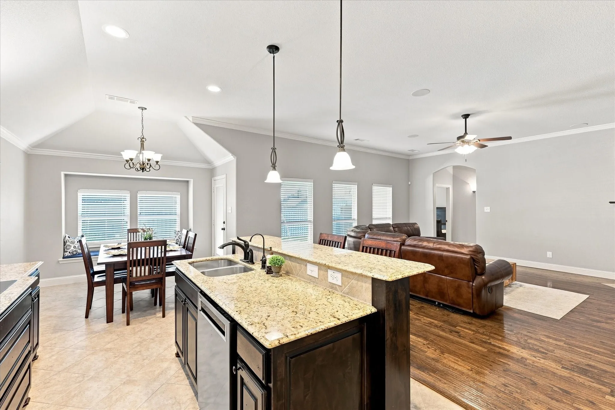Kitchen island with a double basin sink and stainless steel dishwasher, vaulted ceiling, recessed lighting, wood-finish flooring, and a ceiling fan