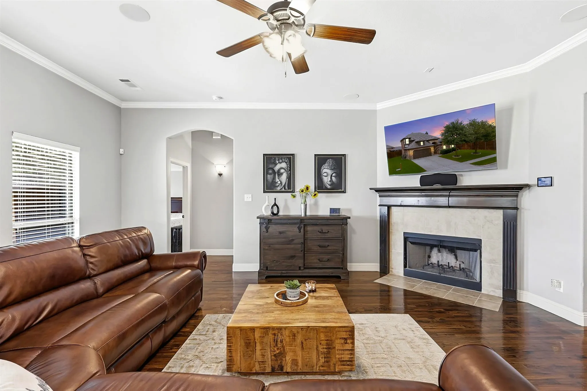Living space featuring wood-finish flooring, a ceiling fan with light fixture, crown molding, and recessed lighting and wood burning fireplace.