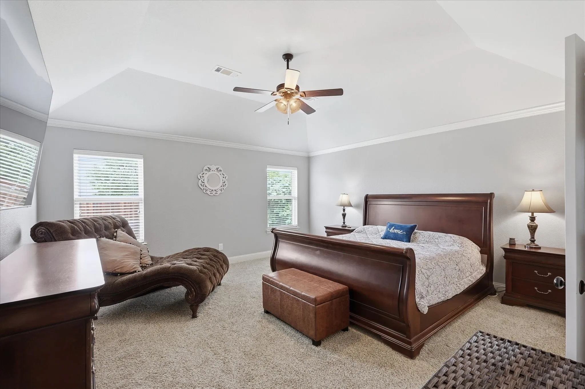 Carpeted interior space featuring a tray ceiling, crown molding, and a ceiling fan with light fixture