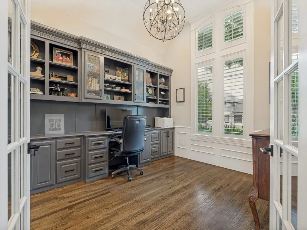 Open the French doors to study with a wall of stately built-ins and desk. Accented by plantation shutters & chandelier.