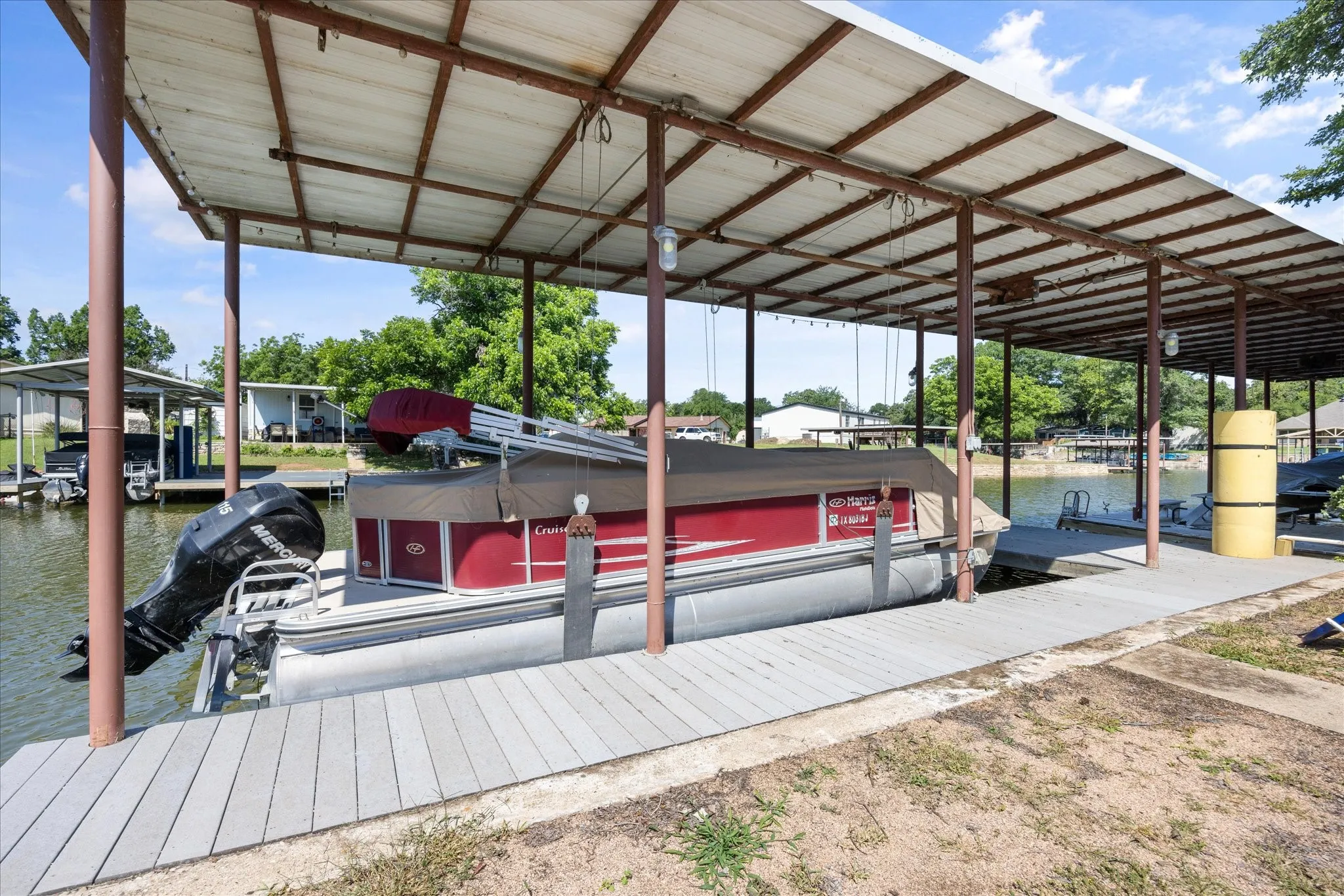 Covered boat dock featuring a metal roof, multiple boat slips, and composite decking