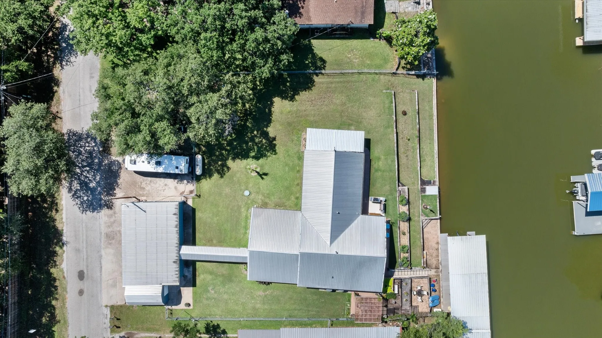 Waterfront property featuring a main residence with a metal roof, an elongated covered walkway, and an additional outbuilding