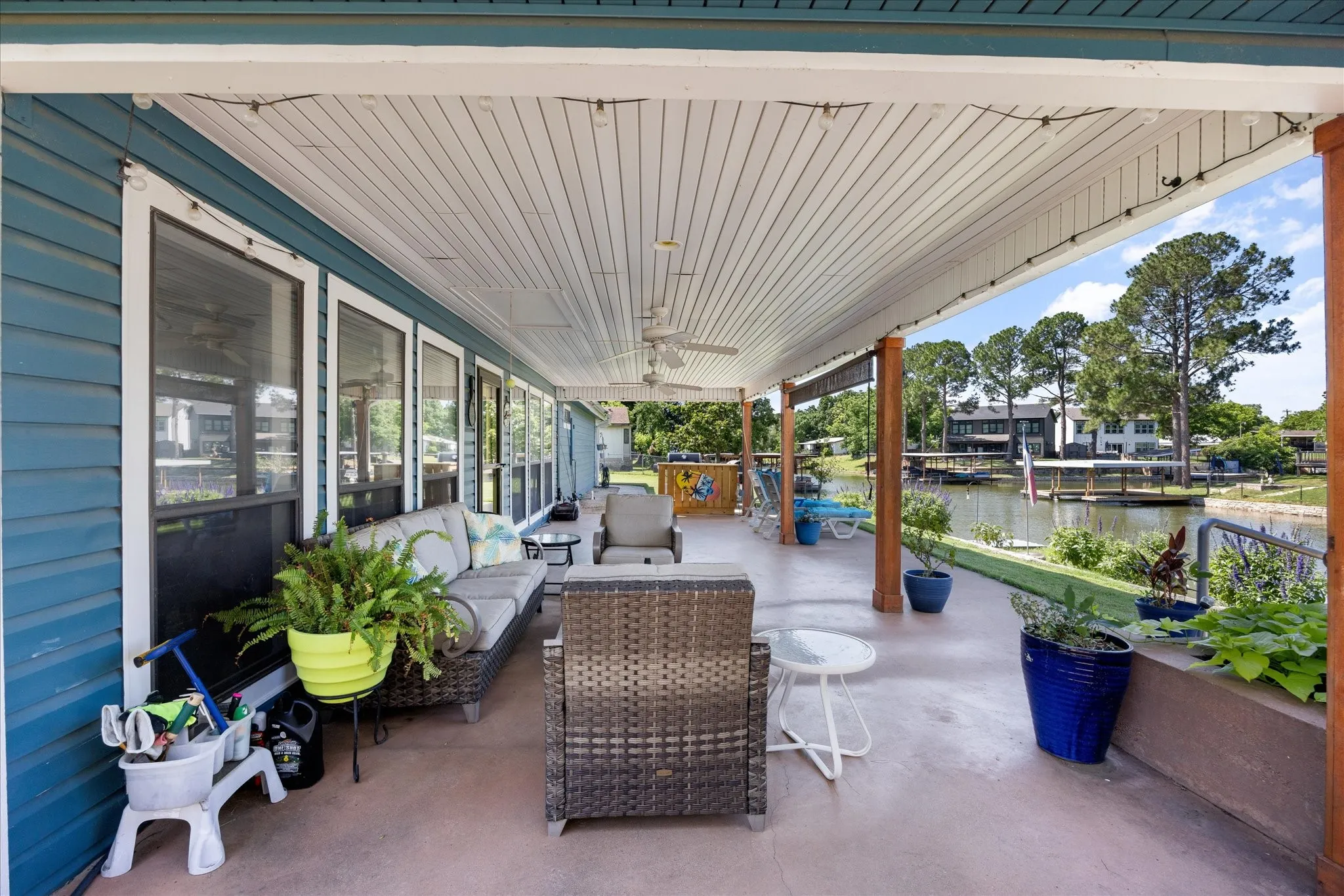 Spacious covered patio with concrete flooring and multiple ceiling fans