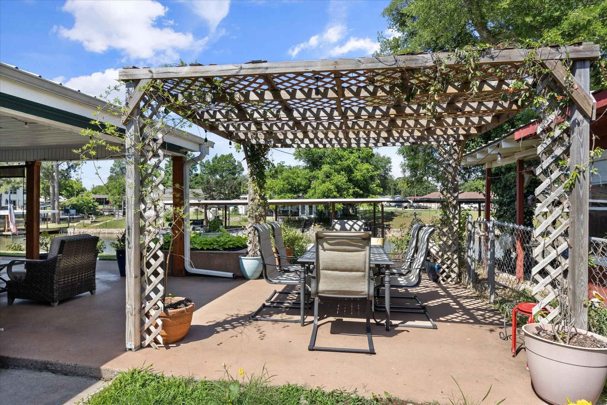 Expansive concrete patio featuring a wooden pergola with lattice detailing and established climbing greenery
