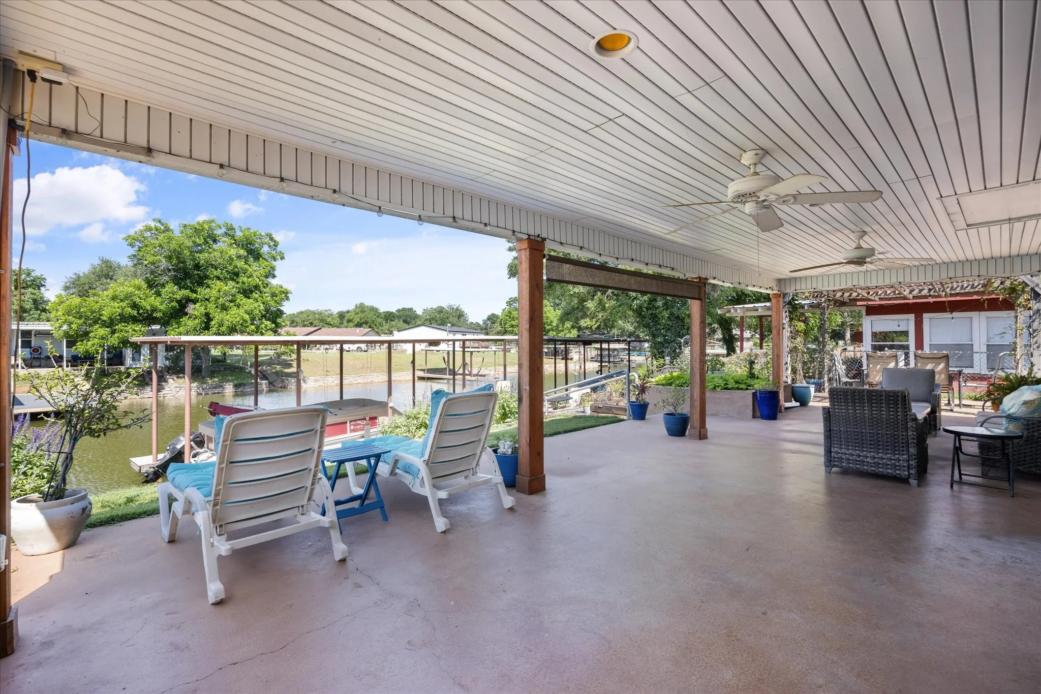 Expansive covered patio with concrete flooring and multiple ceiling fans