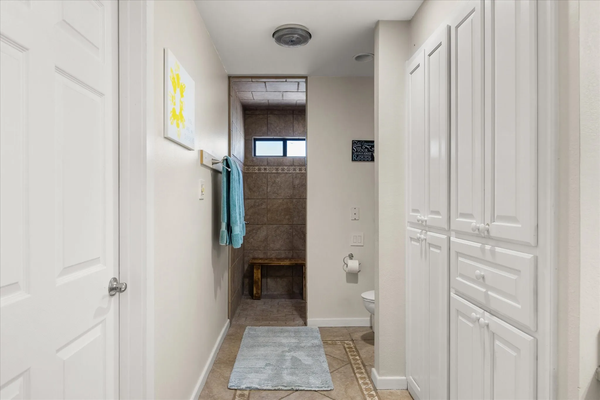Bathroom featuring a walk-in shower with tile surround, a built-in wooden bench, and a small transom window