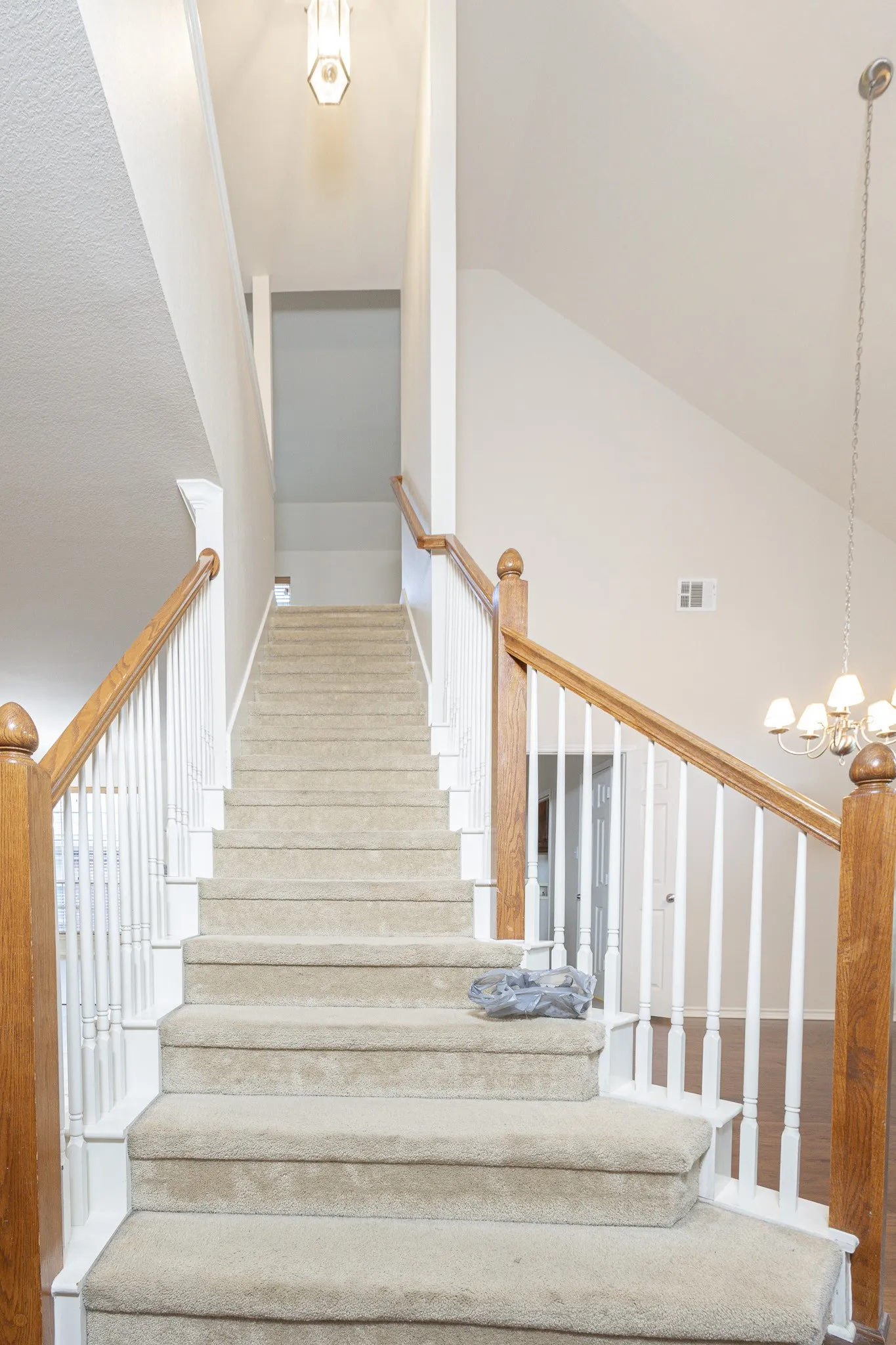 Stairway featuring high vaulted ceiling, an inviting chandelier, and wood-type flooring