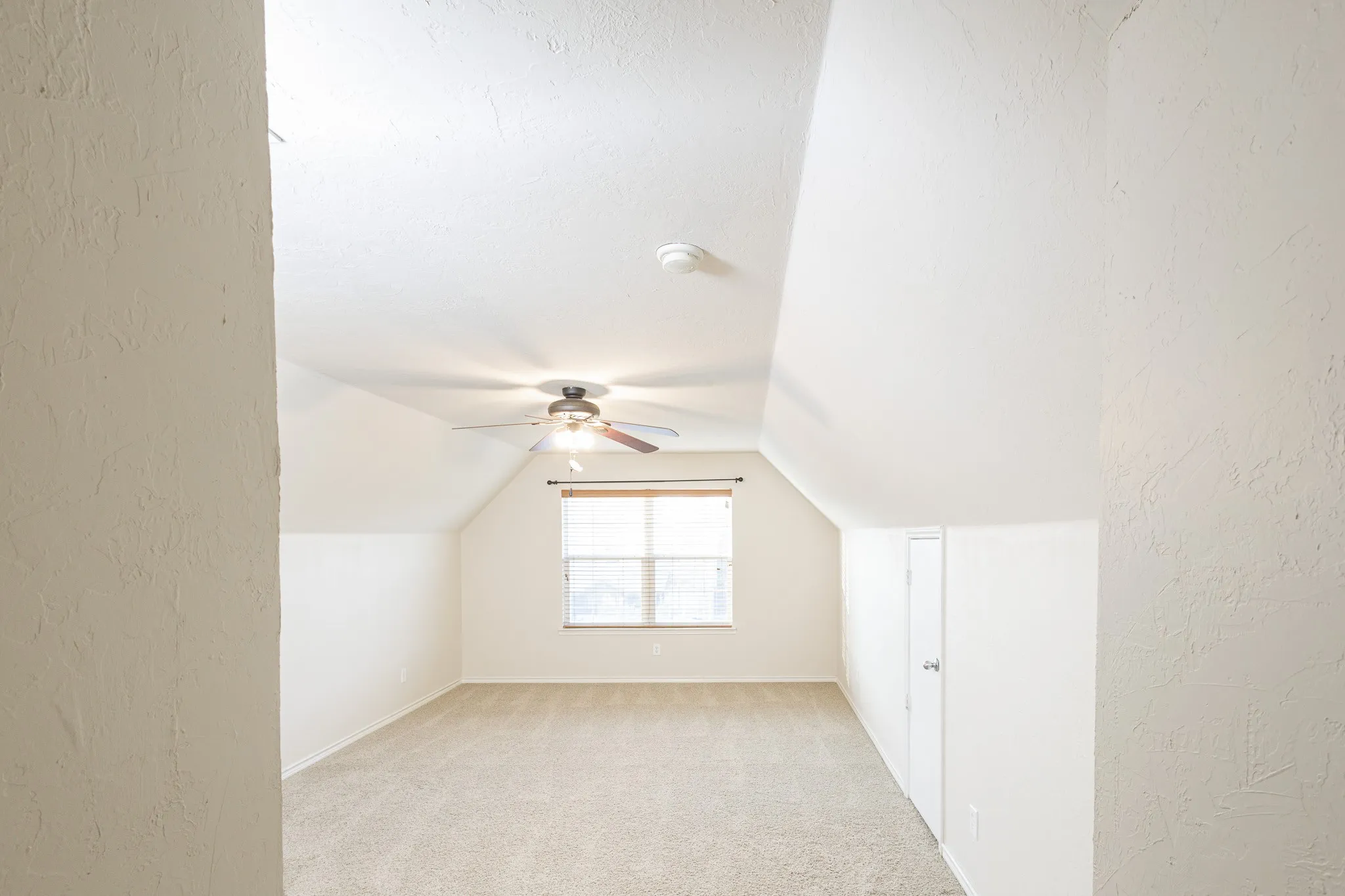 Bonus room with ceiling fan, light colored carpet, and lofted ceiling