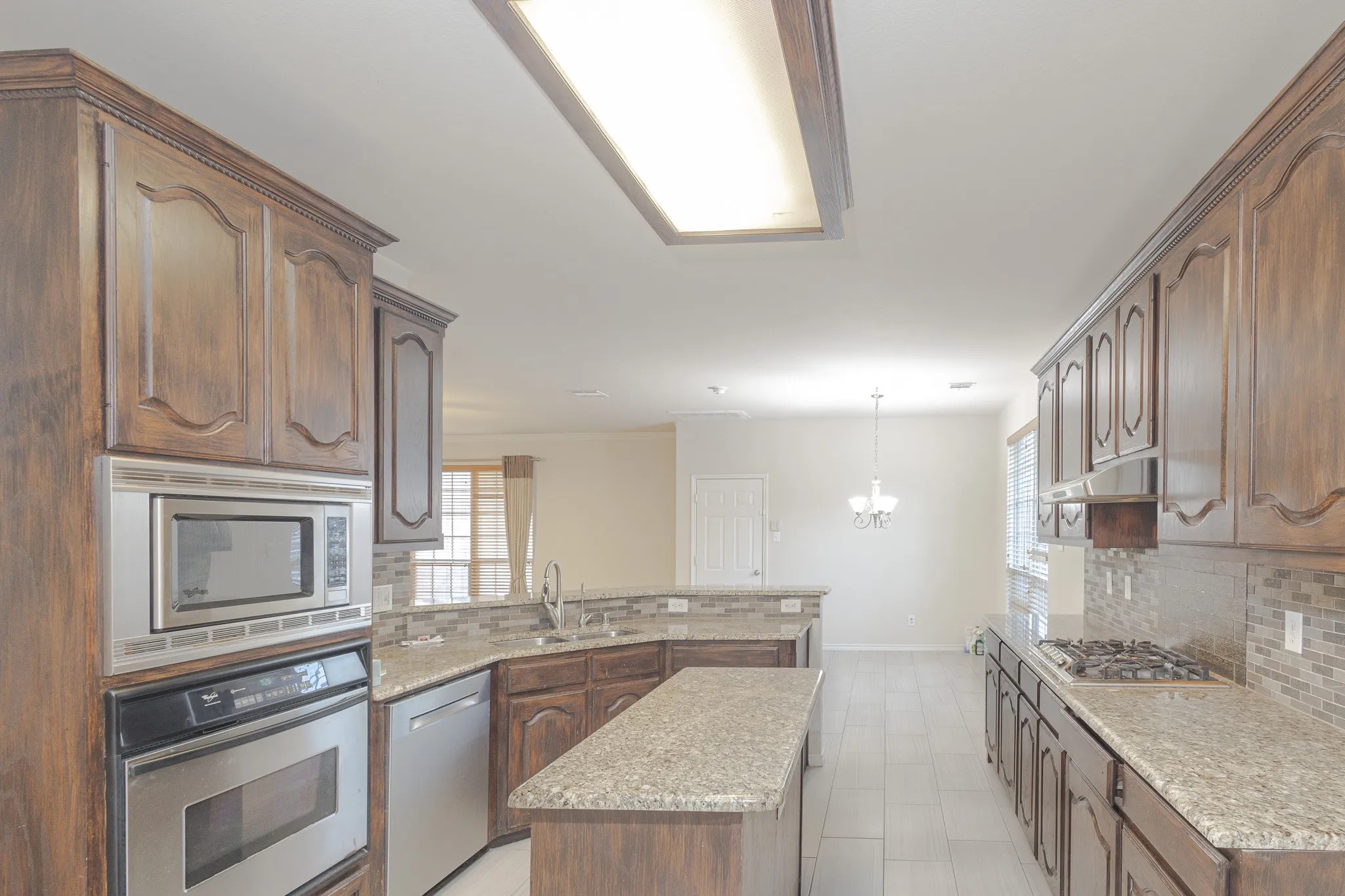Kitchen with a kitchen island, stainless steel appliances, light tile flooring, and backsplash