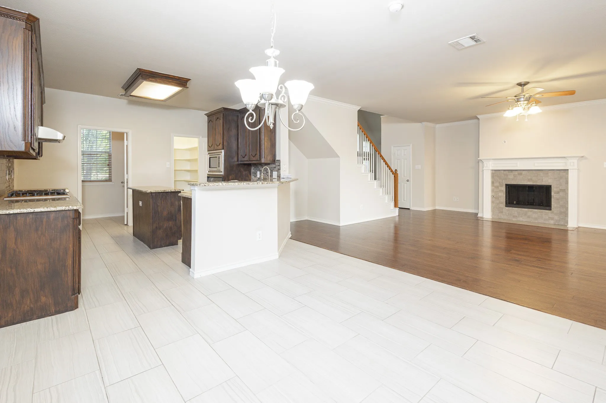 Kitchen featuring light stone countertops, custom exhaust hood, decorative light fixtures, dark brown cabinetry, and backsplash