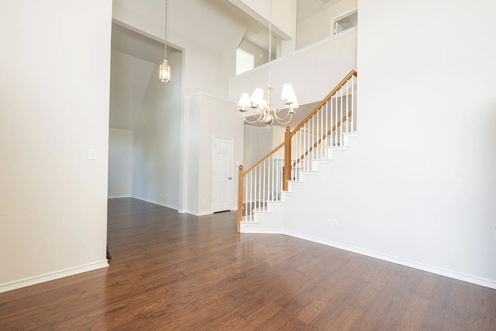 Spare room with dark wood-type flooring, a towering ceiling, and an inviting chandelier