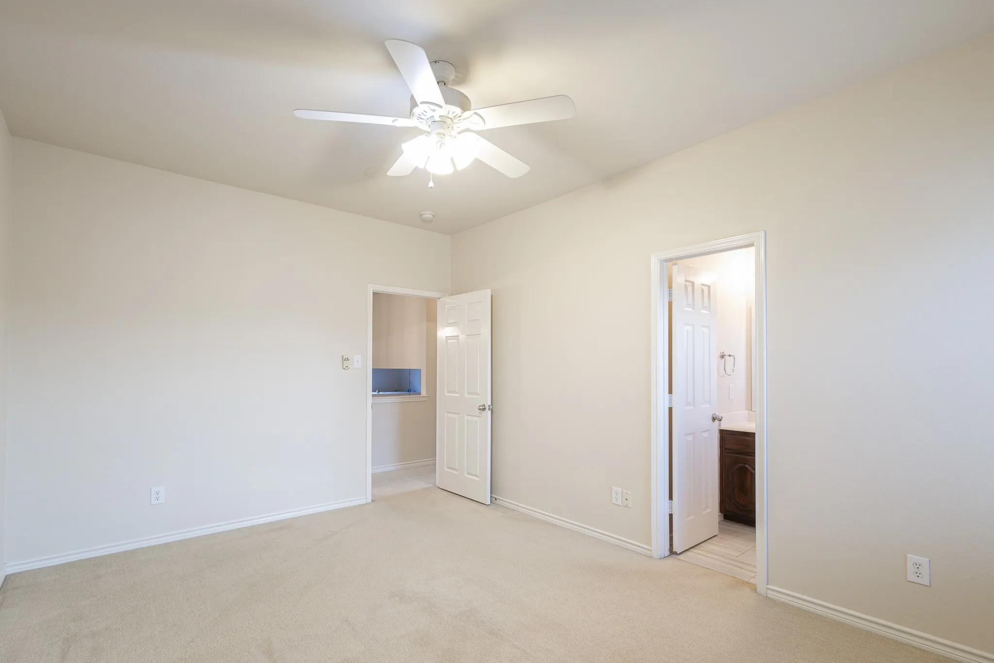 Unfurnished bedroom with light carpet, connected bathroom, and ceiling fan