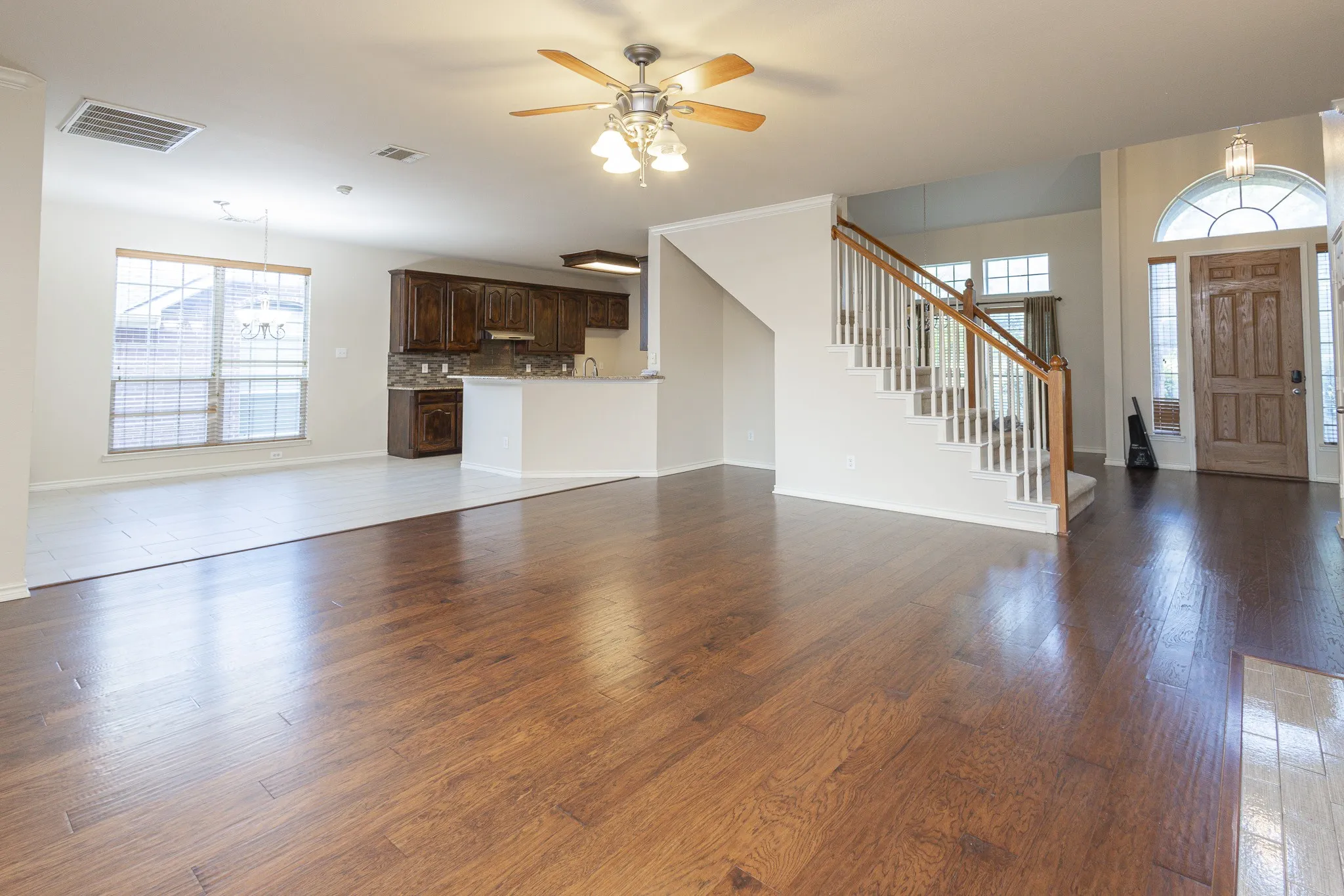 Unfurnished living room featuring ceiling fan and dark hardwood / wood-style flooring