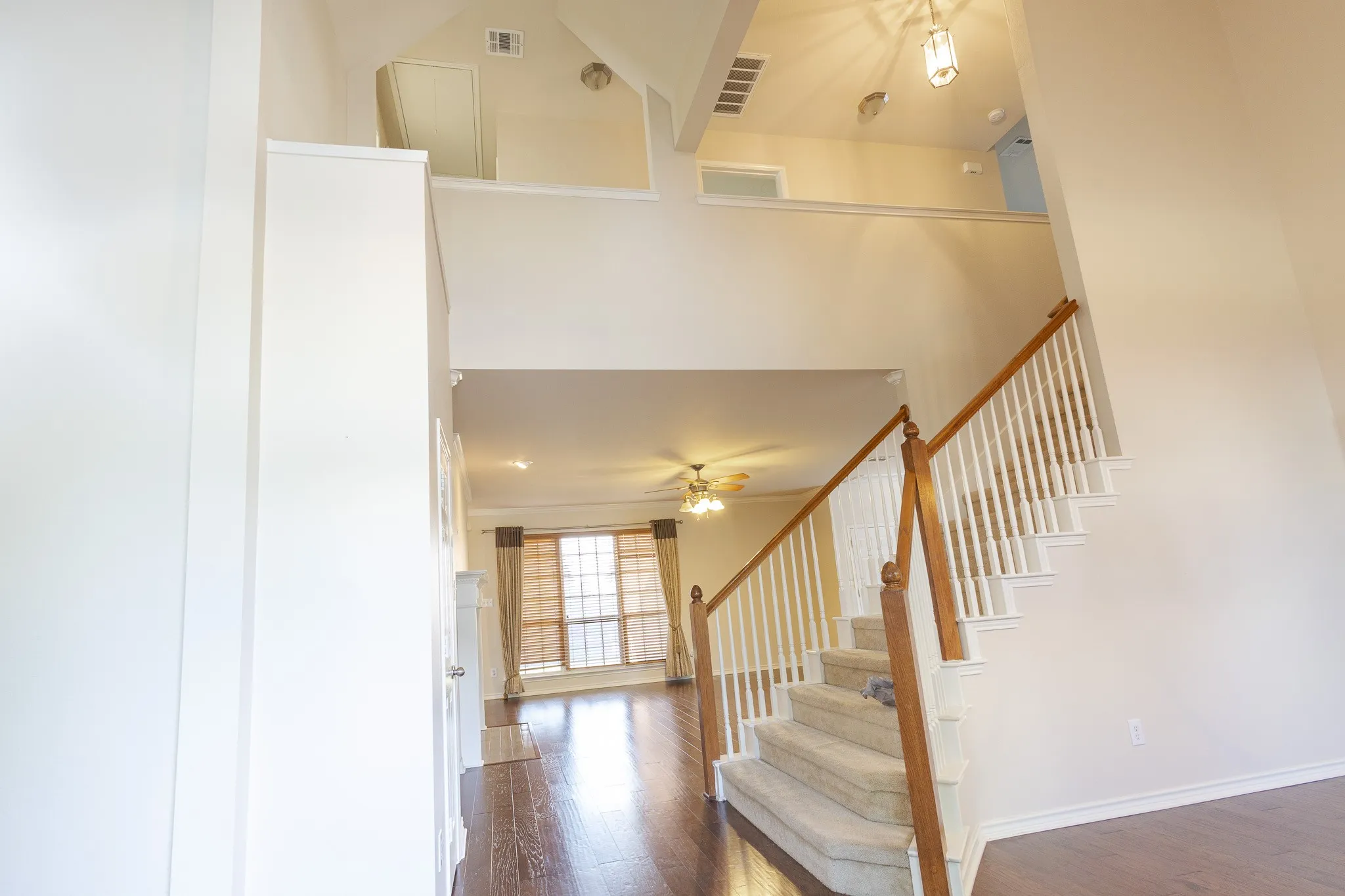 Stairway featuring a high ceiling, ceiling fan, and dark wood-type flooring