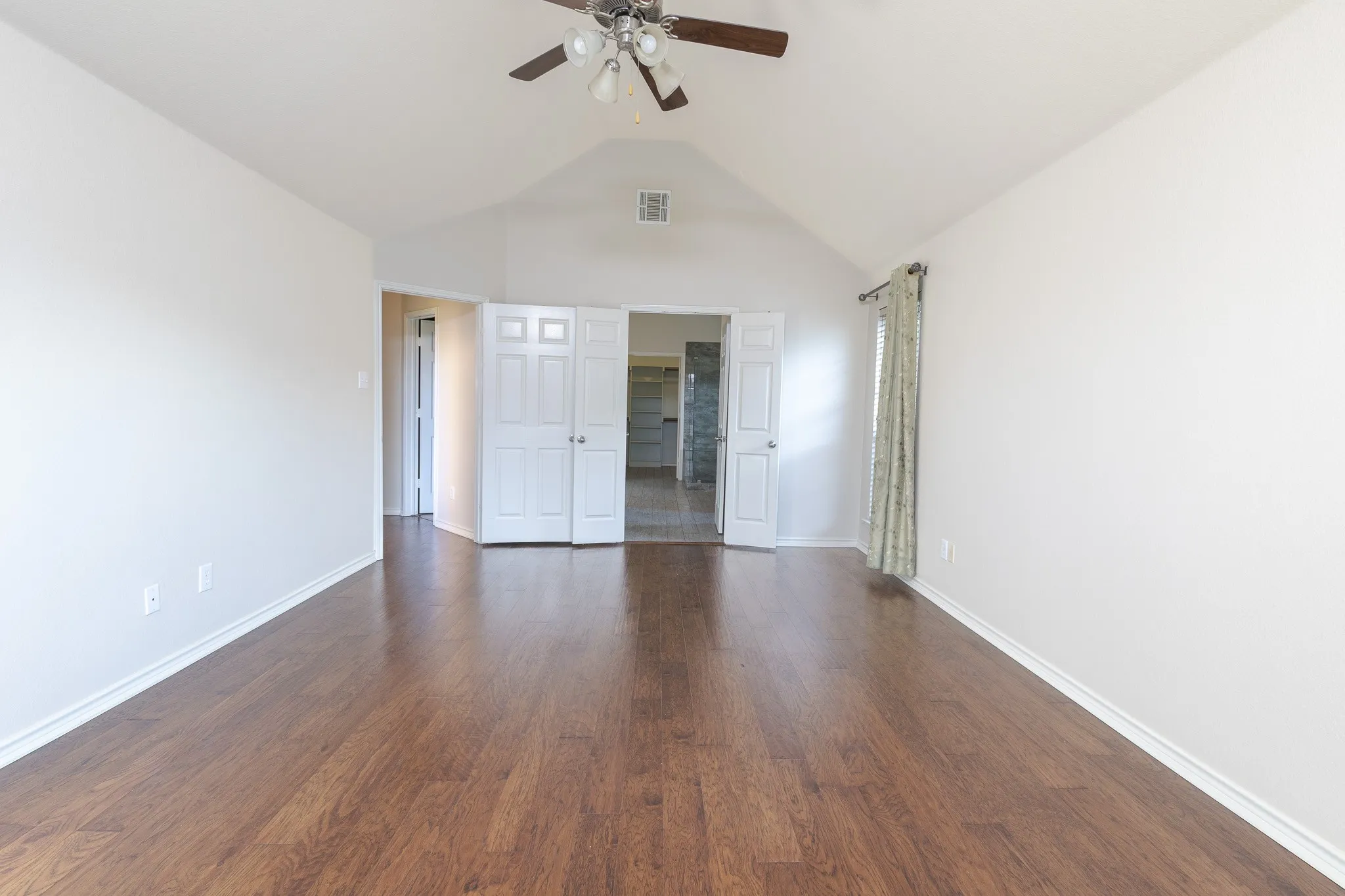 Unfurnished bedroom with ceiling fan, dark hardwood / wood-style floors, and lofted ceiling