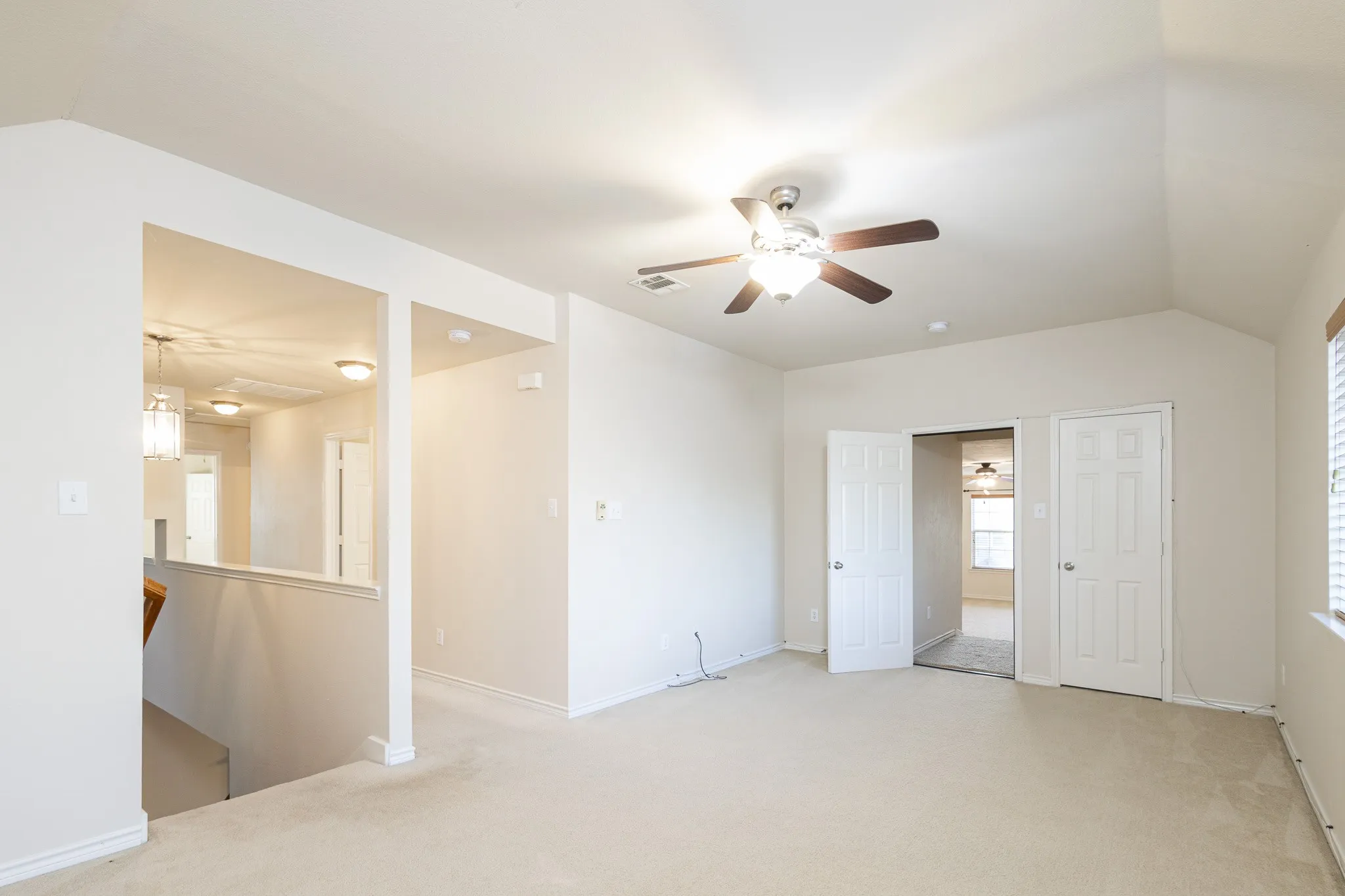 Unfurnished room featuring light carpet, lofted ceiling, and ceiling fan
