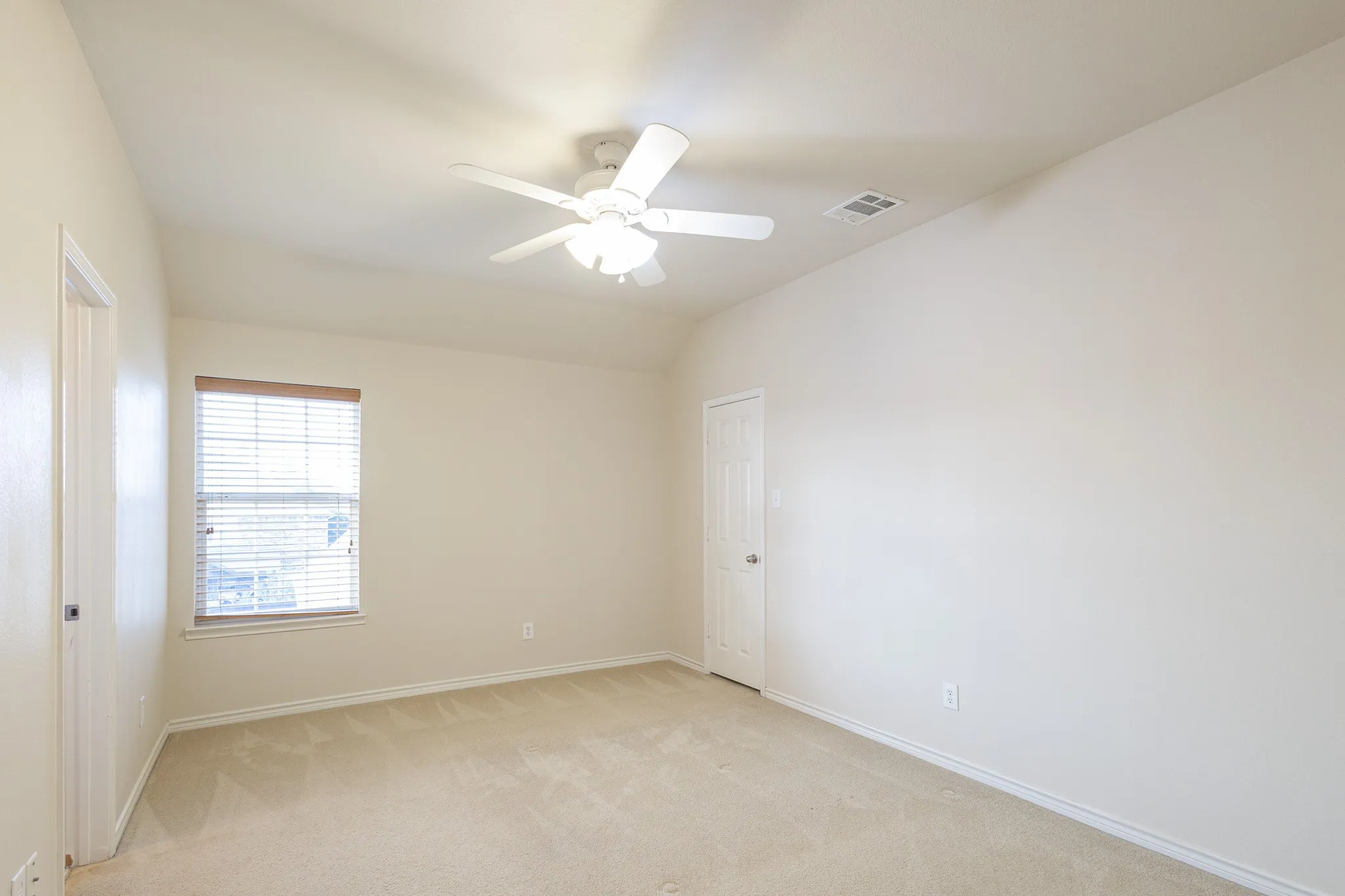 Carpeted empty room with ceiling fan and vaulted ceiling