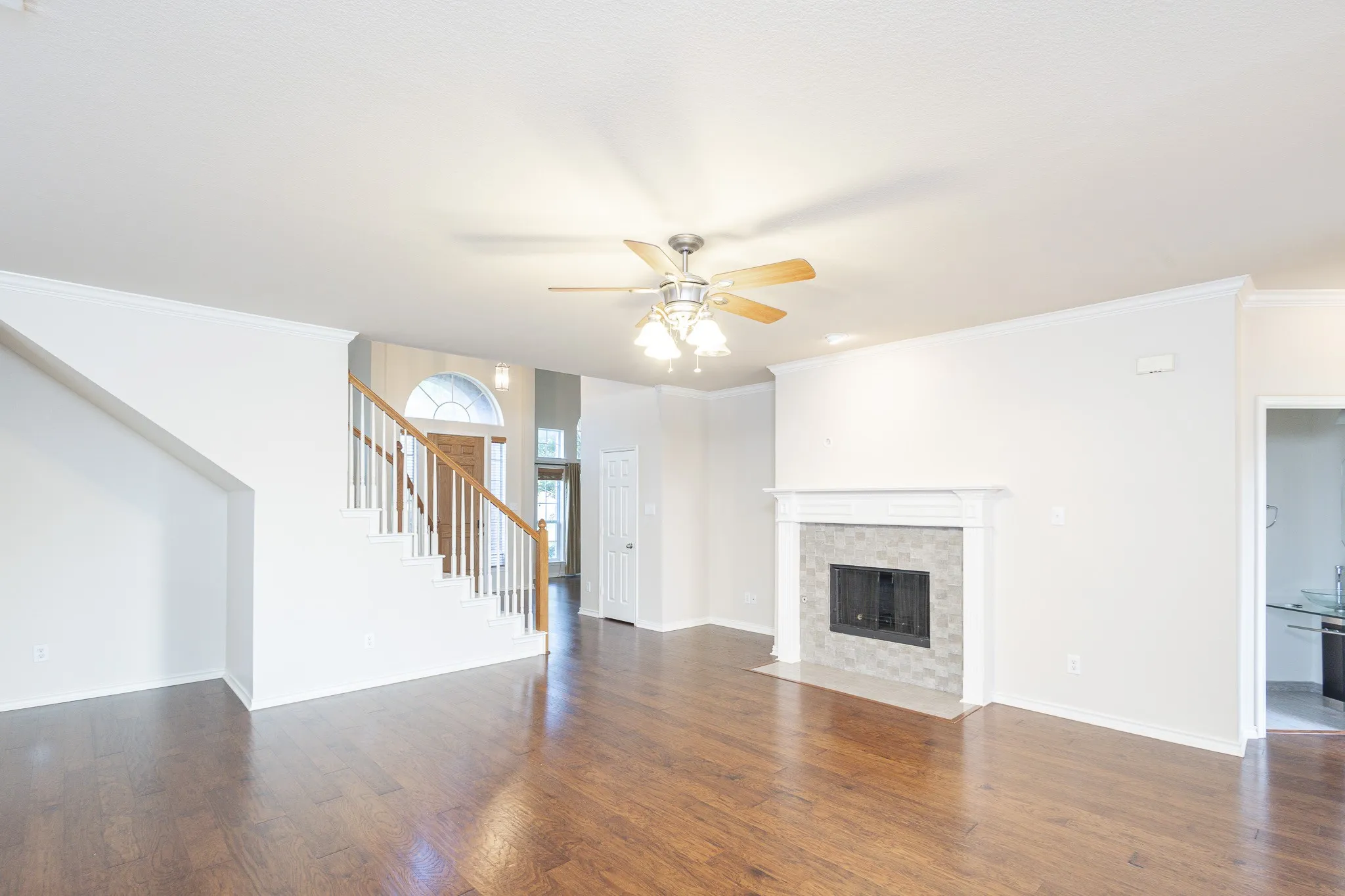 Unfurnished living room featuring dark hardwood / wood-style floors, ceiling fan, a tiled fireplace, and crown molding