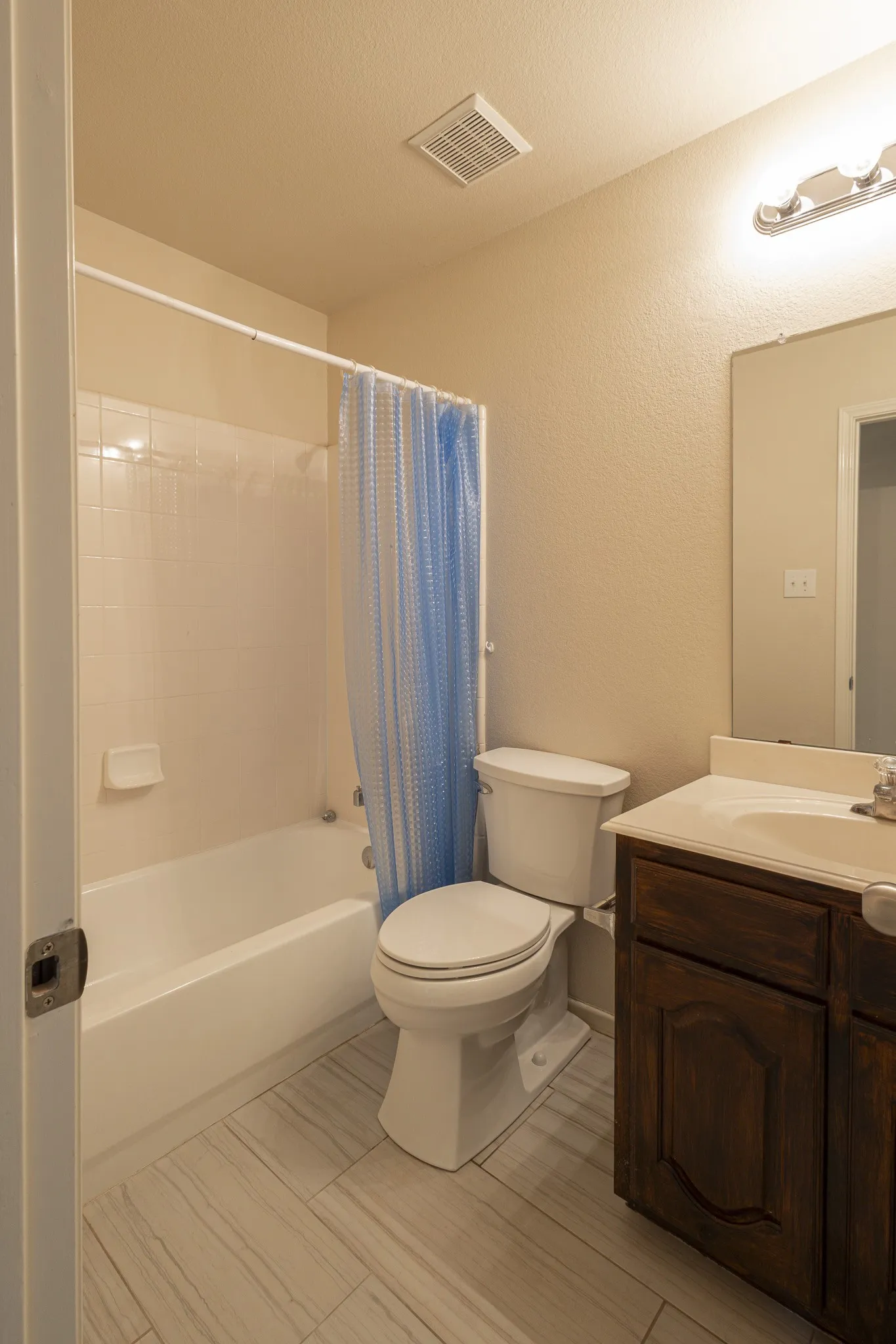 Full bathroom with shower / bath combo with shower curtain, vanity, toilet, and tile flooring