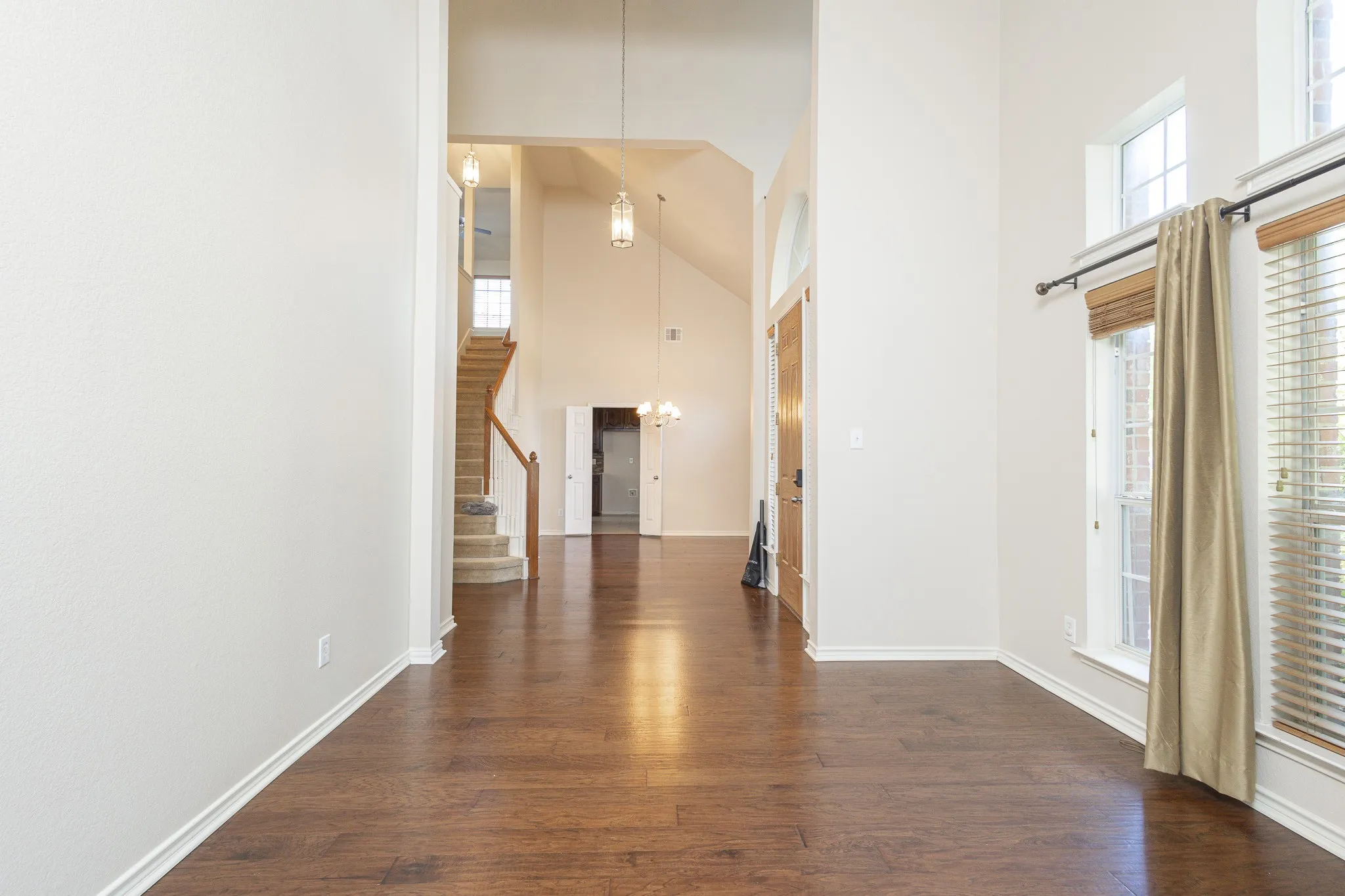 Hallway with high vaulted ceiling and dark hardwood / wood-style floors