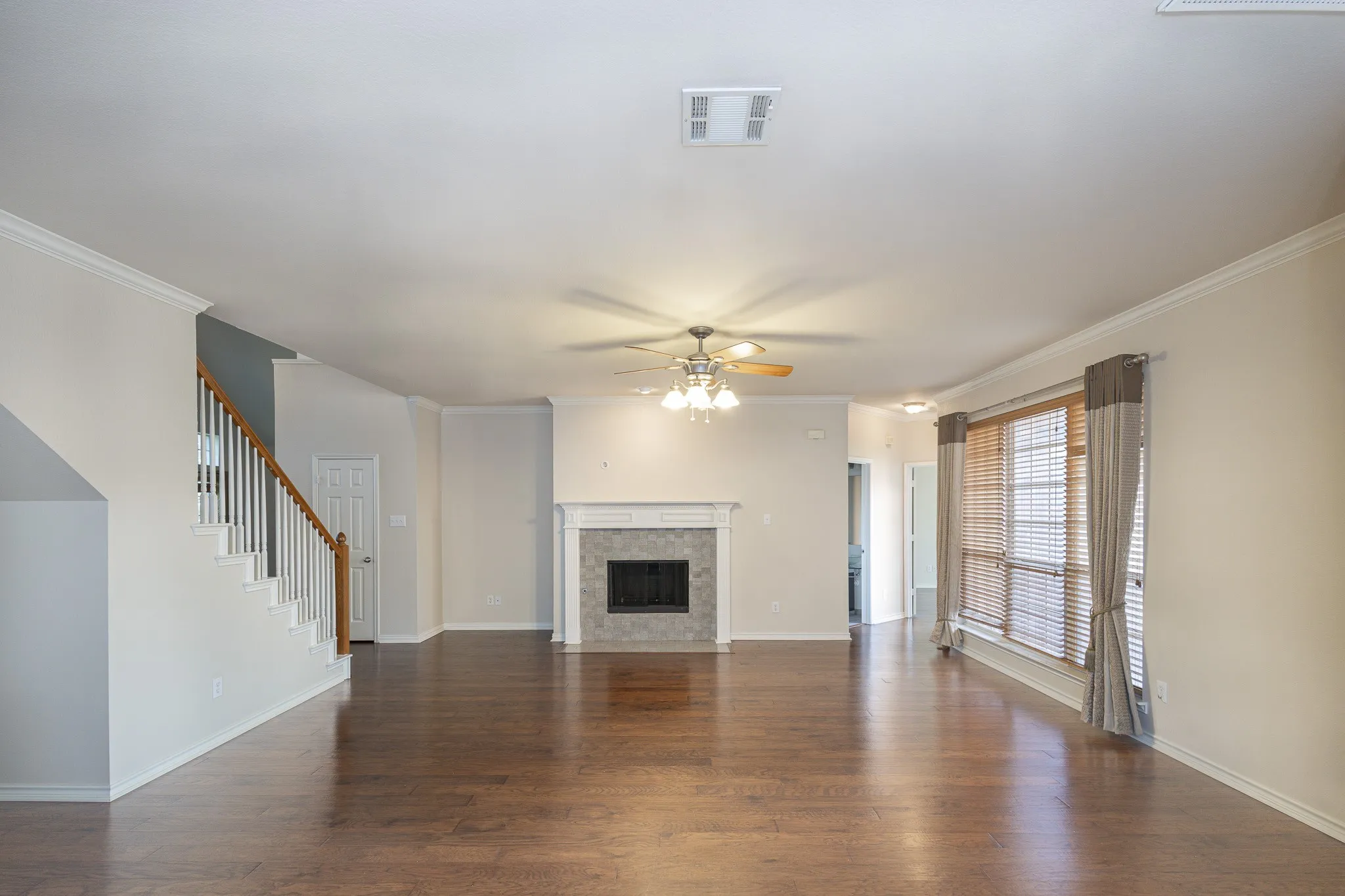 Unfurnished living room featuring ceiling fan, dark hardwood / wood-style flooring, and crown molding