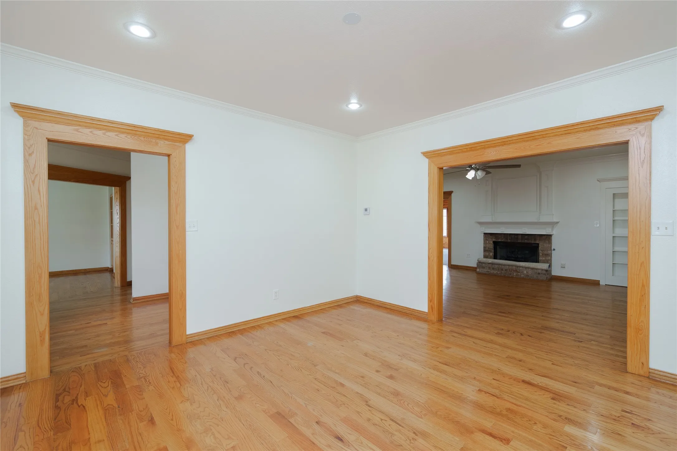 Warm wood-finish flooring throughout, complemented by crisp white walls and recessed lighting