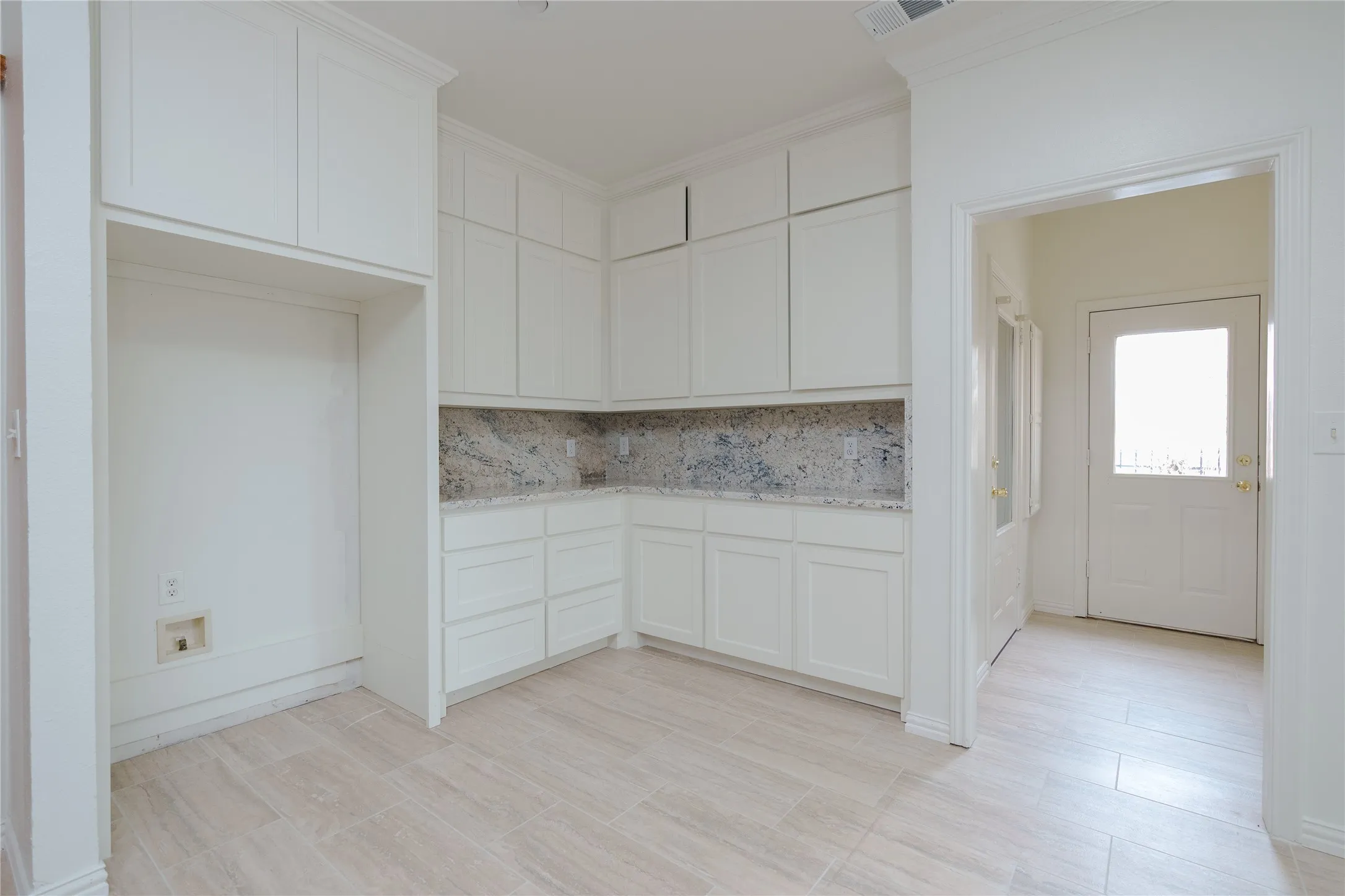 Kitchen area featuring extensive white shaker cabinetry, speckled countertops, a matching backsplash, and light wood-finish flooring
