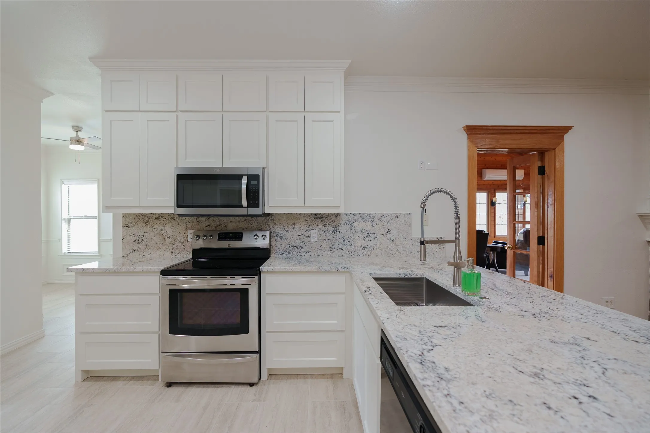 Newly remodeled, spacious kitchen and new appliances, featuring white cabinetry, stainless steel appliances, a double basin sink, and ample counter space with a light-toned stone finish