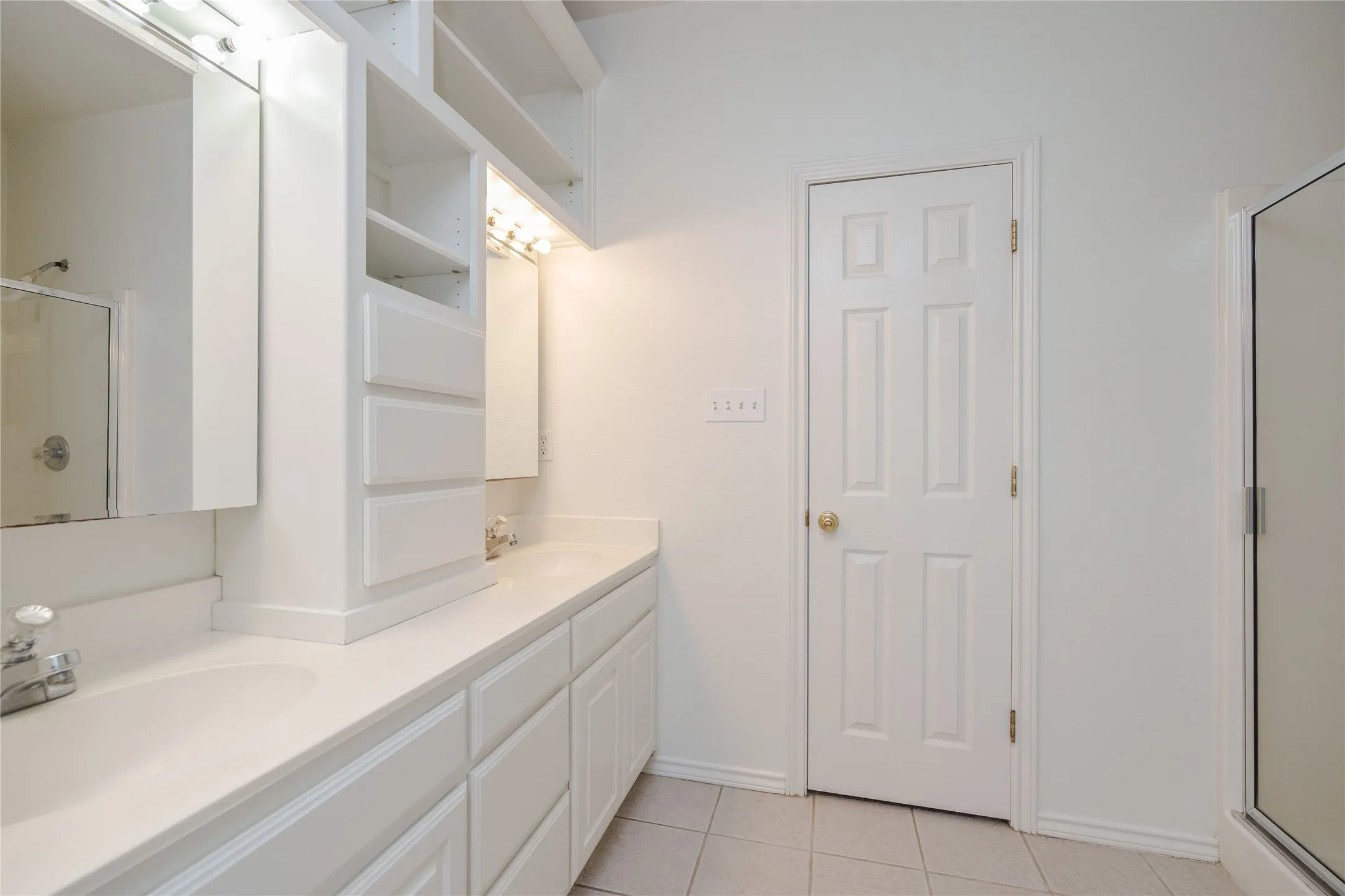 Dual vanity with integrated sinks, white cabinetry, integrated shelving, and tile flooring