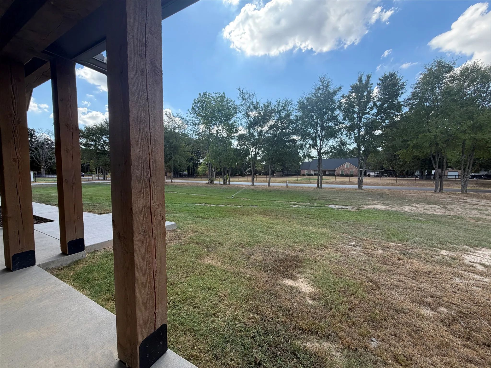 Exposed beam construction with a concrete porch and a large grassy area