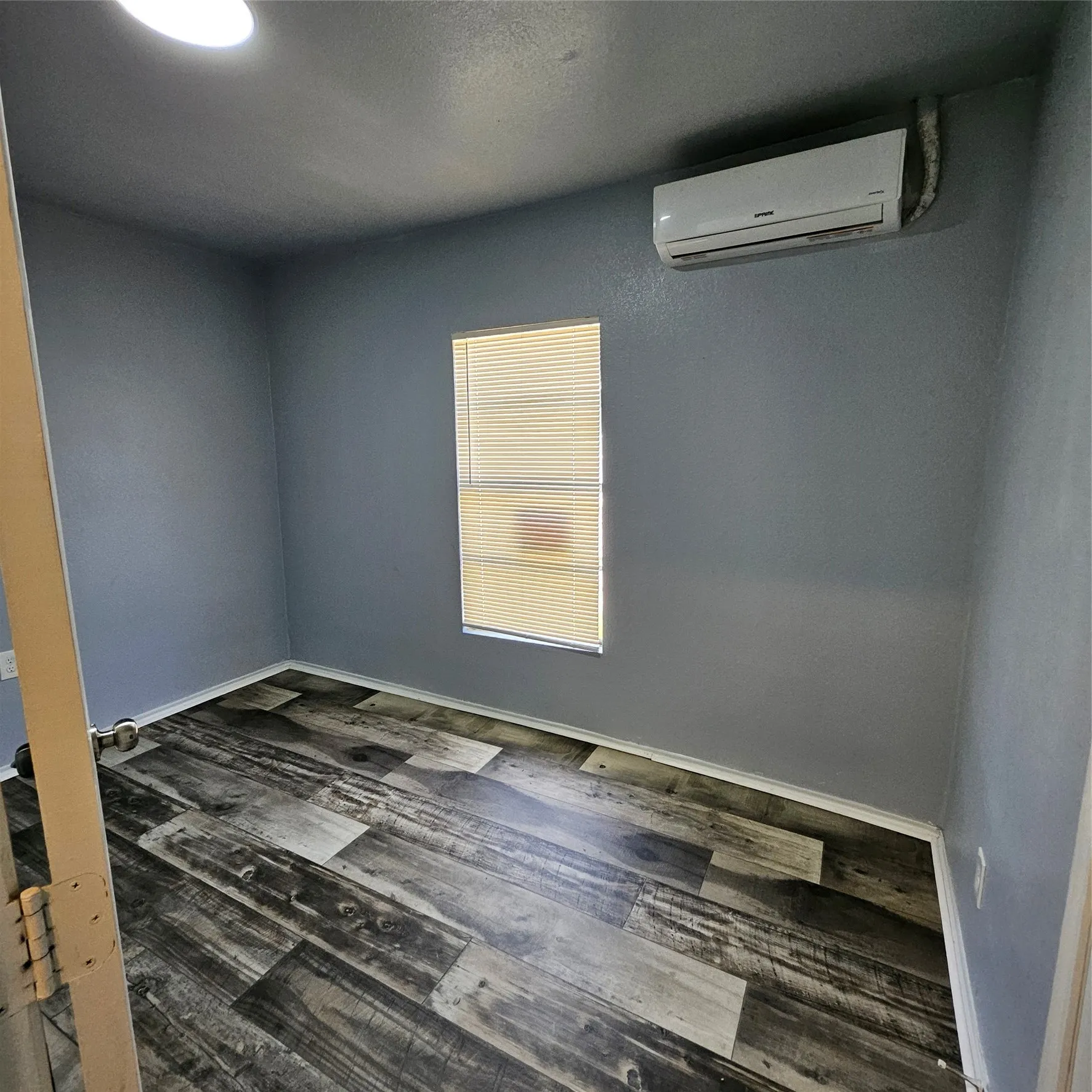 Room with wood-finish flooring, gray walls, and white baseboards