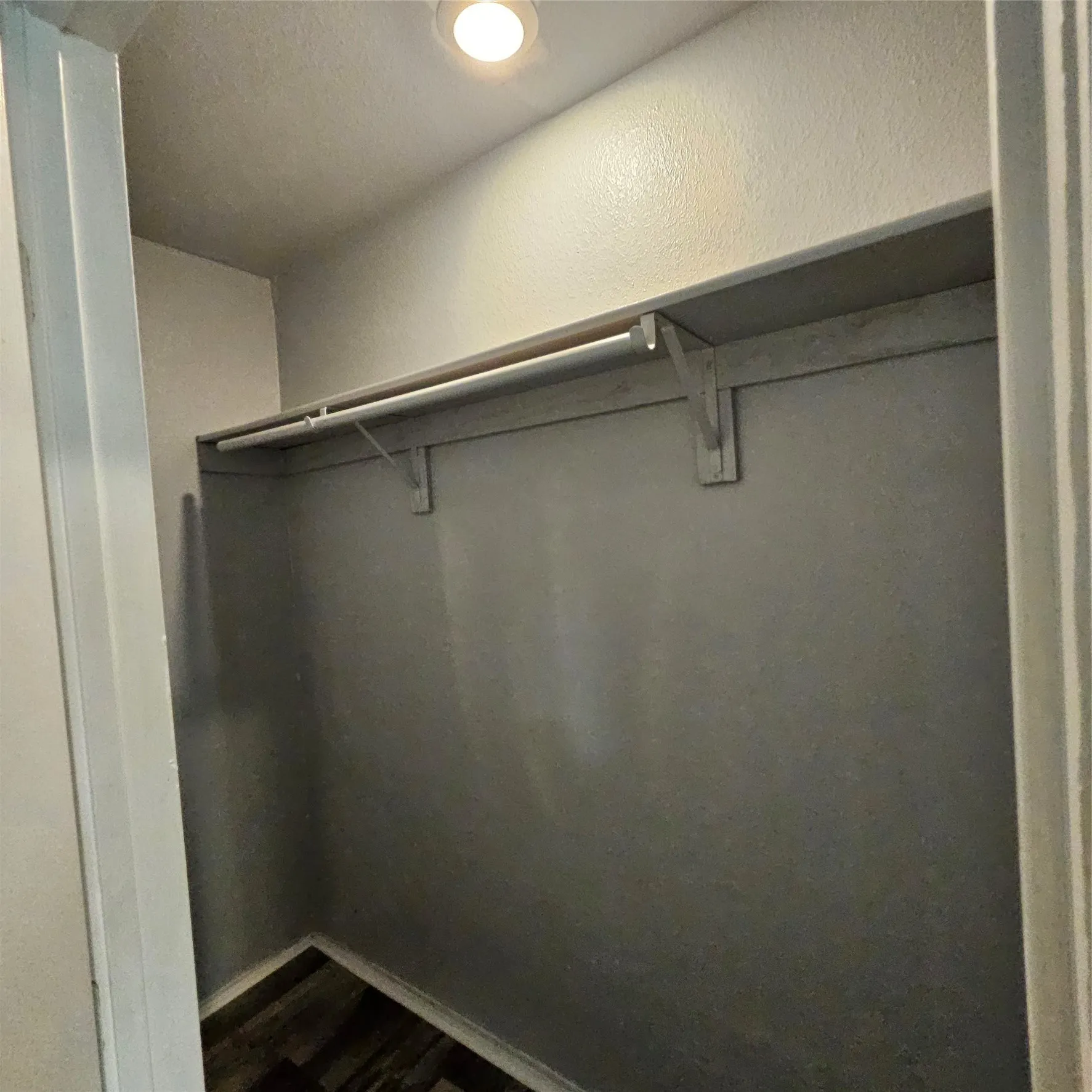Recessed lighting illuminates this closet, featuring a built-in shelf and hanging rod