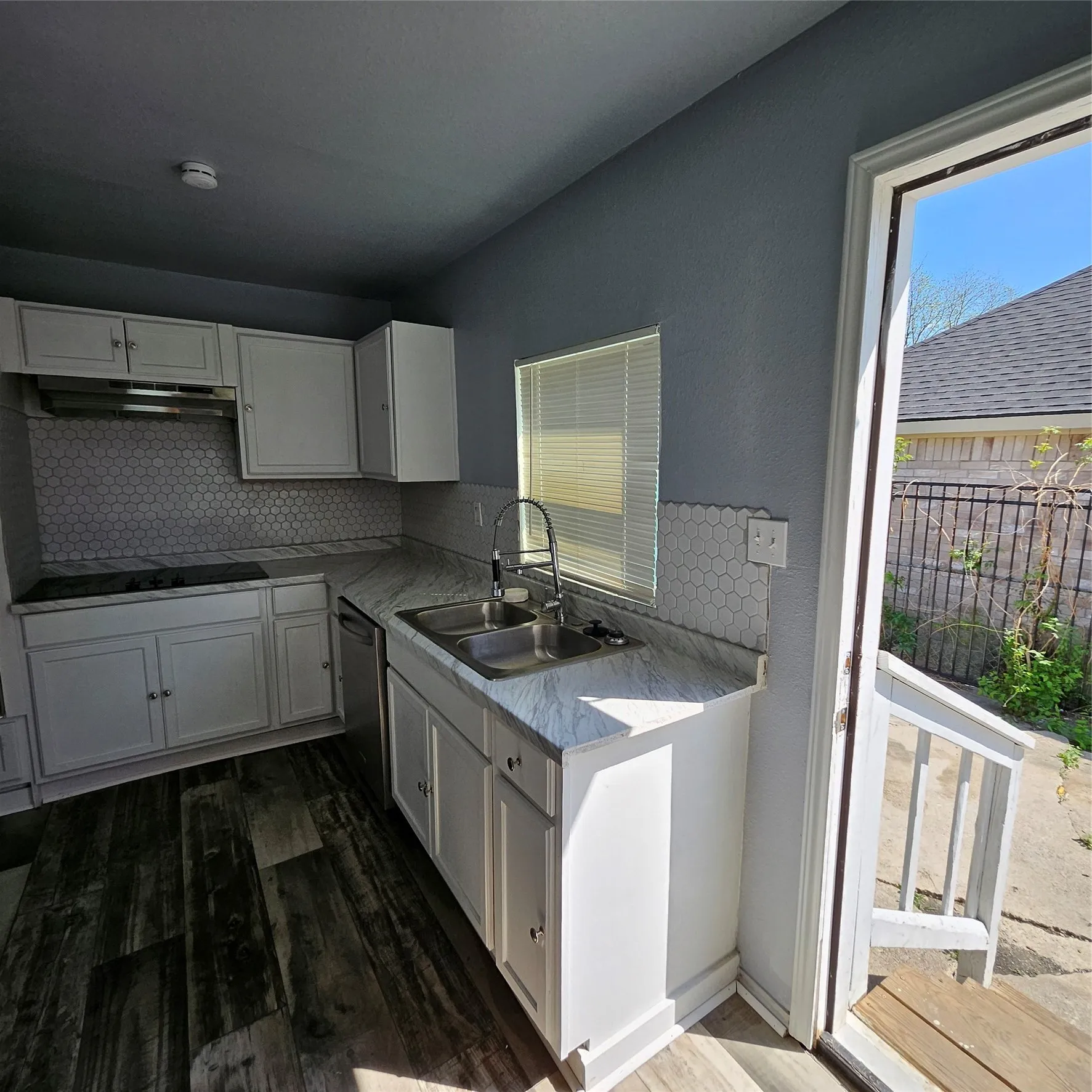 Kitchen featuring white cabinetry, wood-finish flooring, and a hexagon tile backsplash