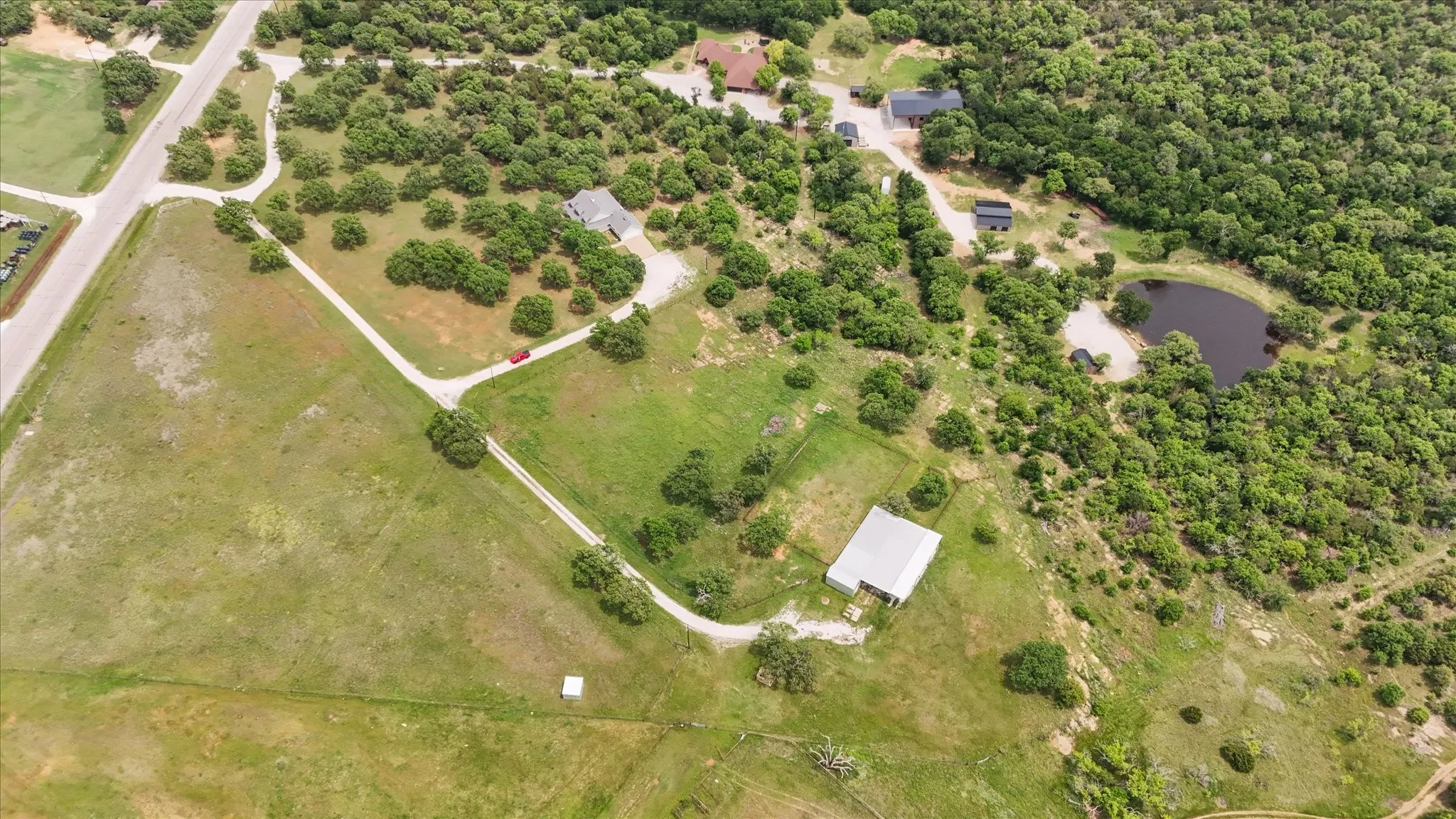 Expansive property featuring a private pond, multiple structures, and extensive tree cover