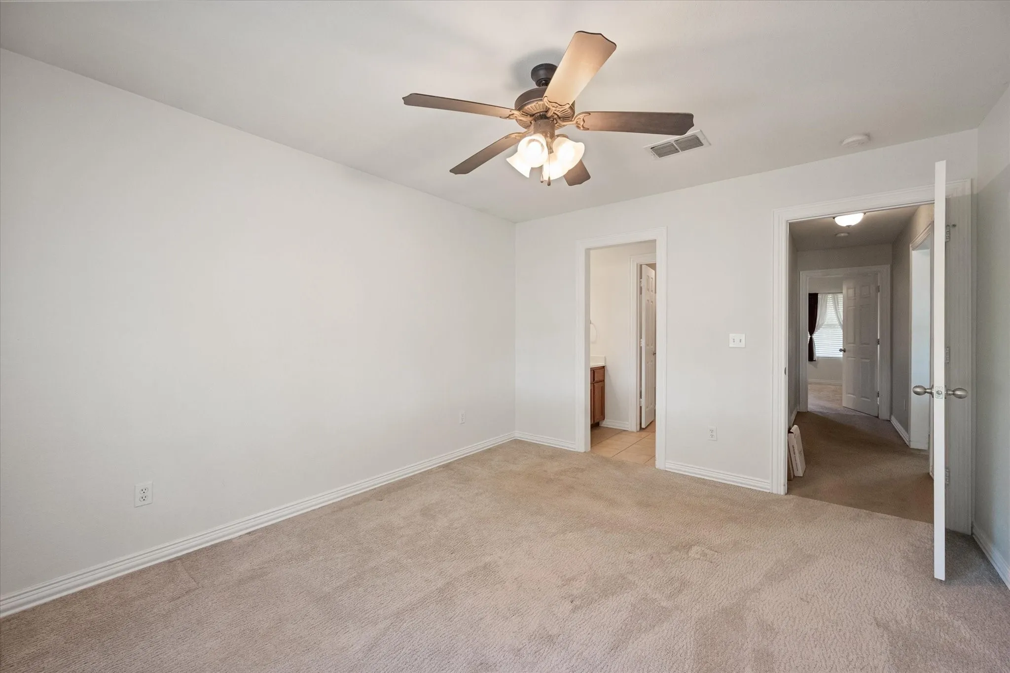 Carpeted interior room featuring light neutral wall paint and a ceiling fan with integrated lighting