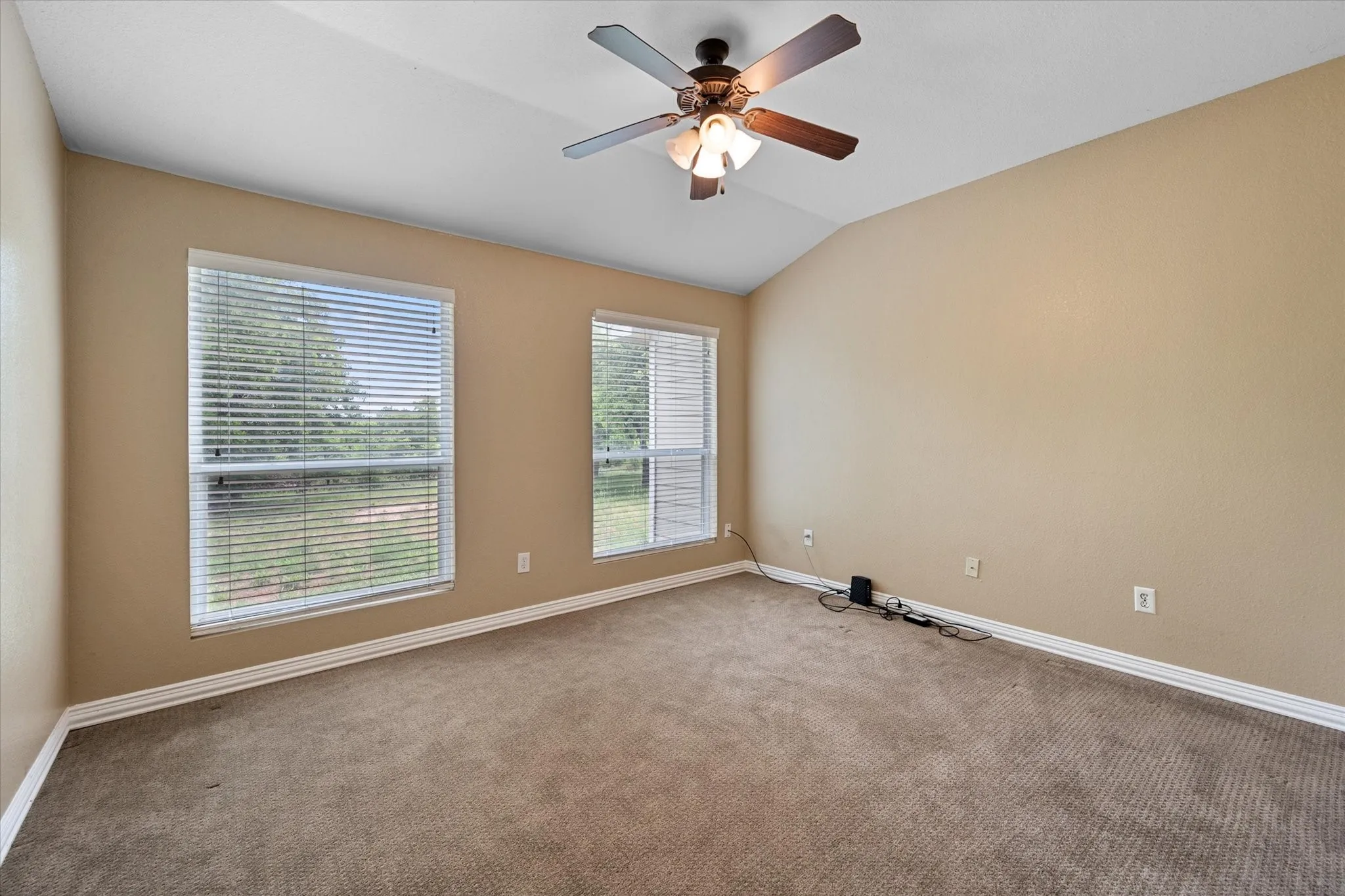 Room featuring vaulted ceilings, neutral-toned walls, and soft carpet flooring