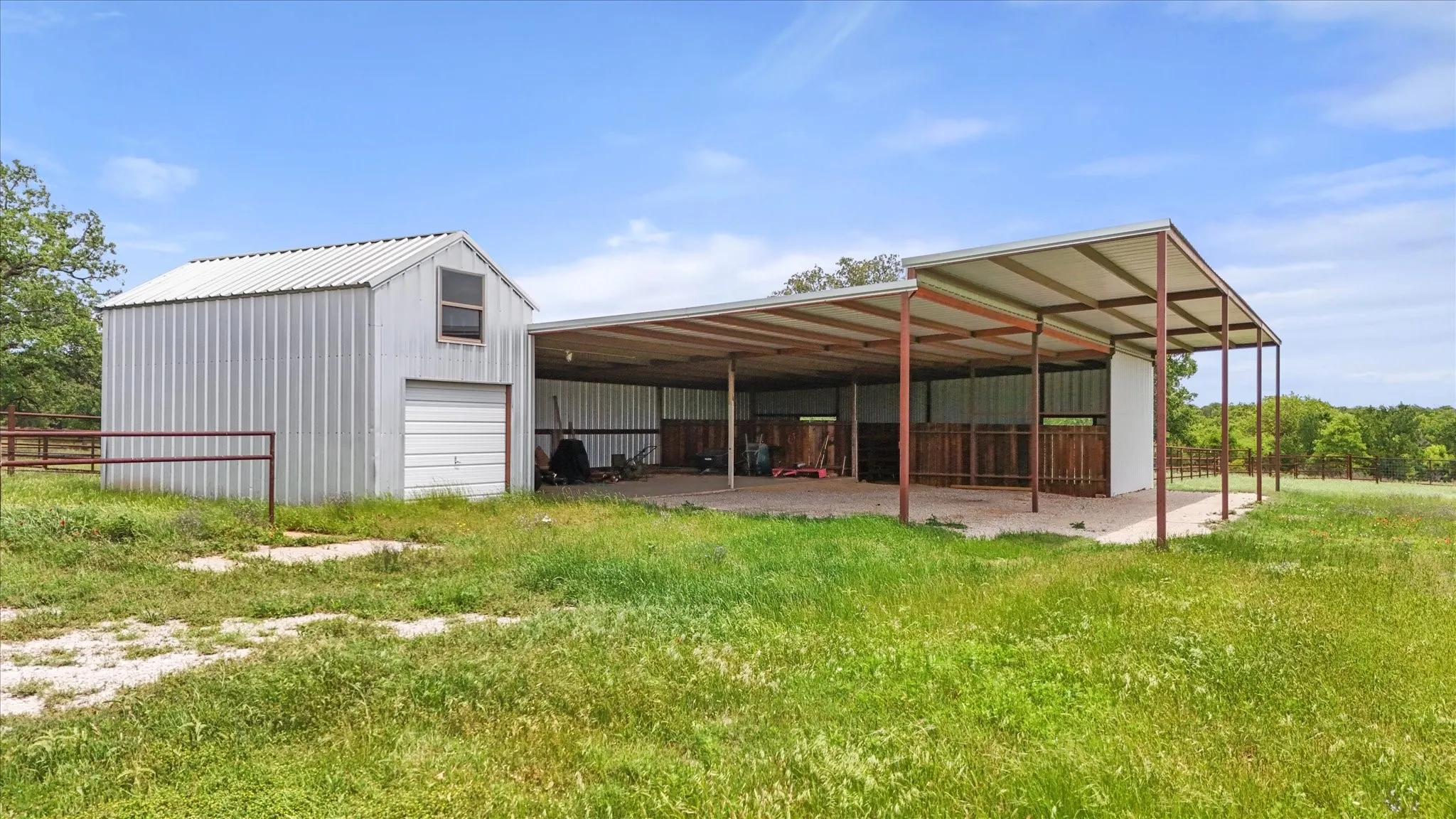 Corrugated metal barn structure featuring a roll-up garage door and an upper-level window