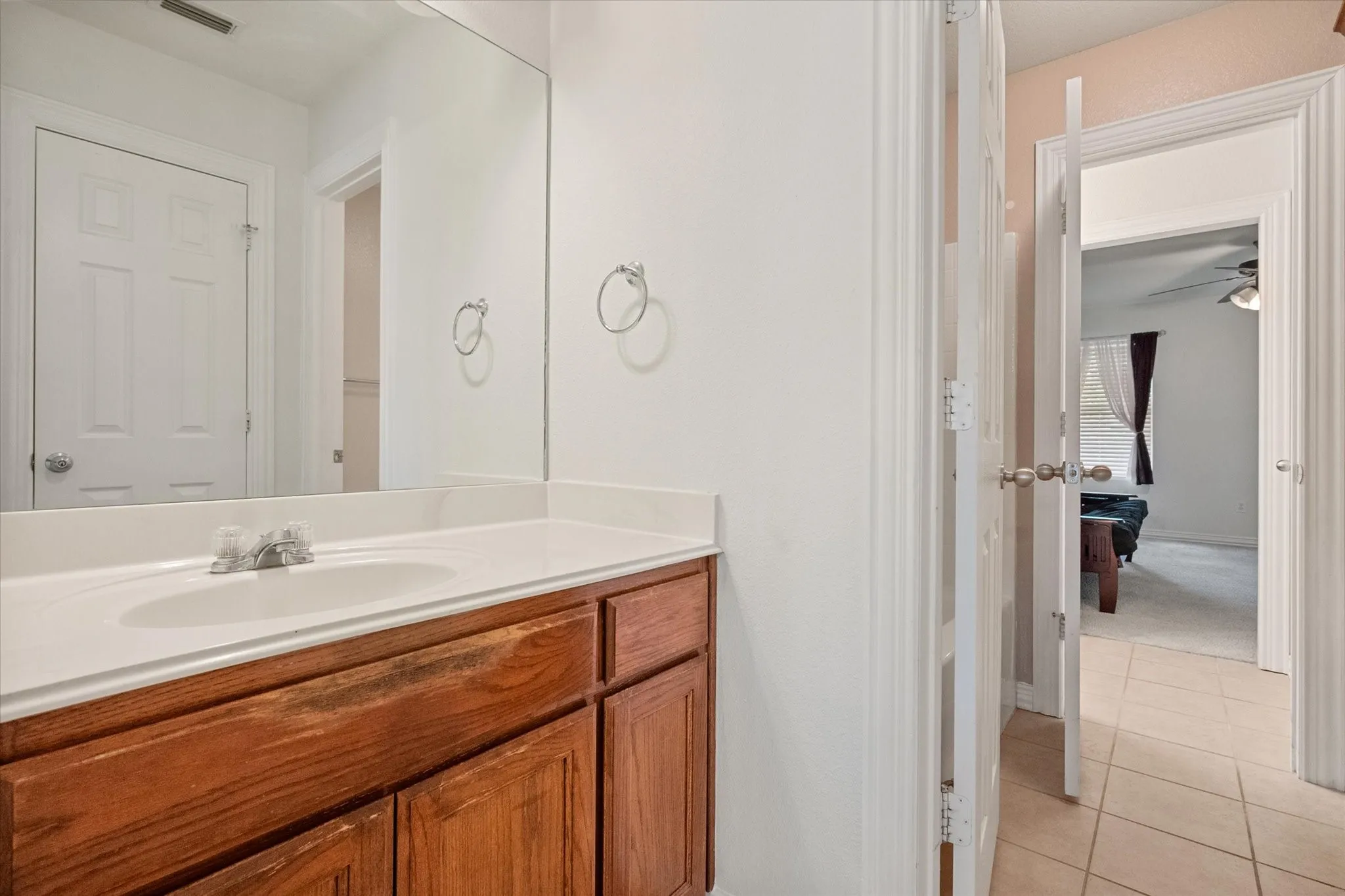 Bathroom vanity featuring a single basin, integrated countertop, and wood-finish cabinetry