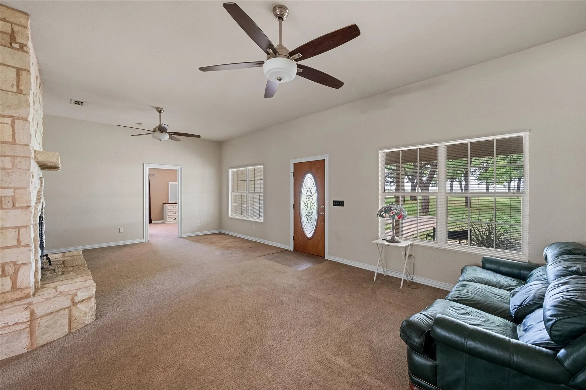 Spacious interior with vaulted ceilings, a stone fireplace, and multiple windows providing outdoor scenery