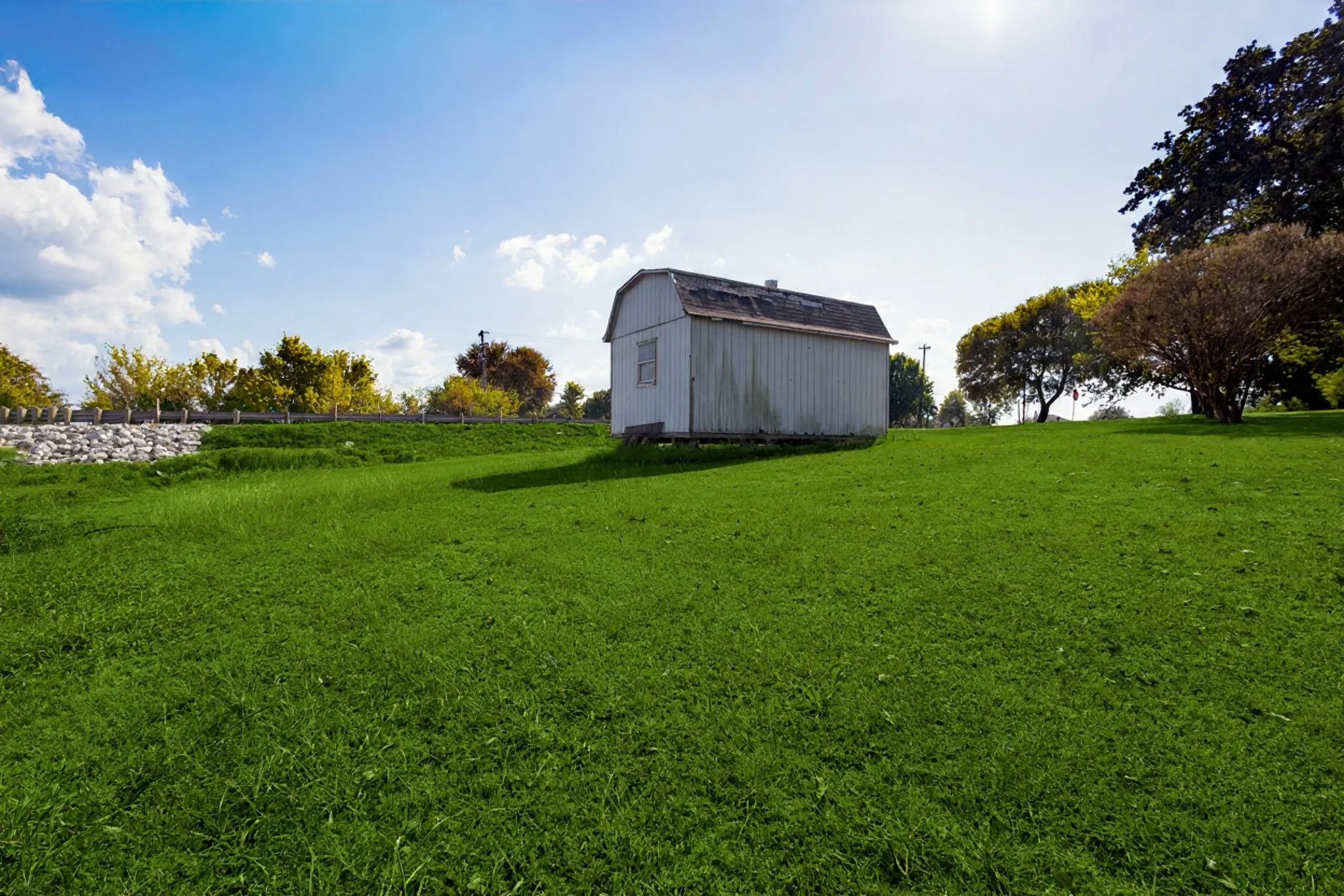 Expansive green lawn with a white outbuilding featuring a barn-style roof
