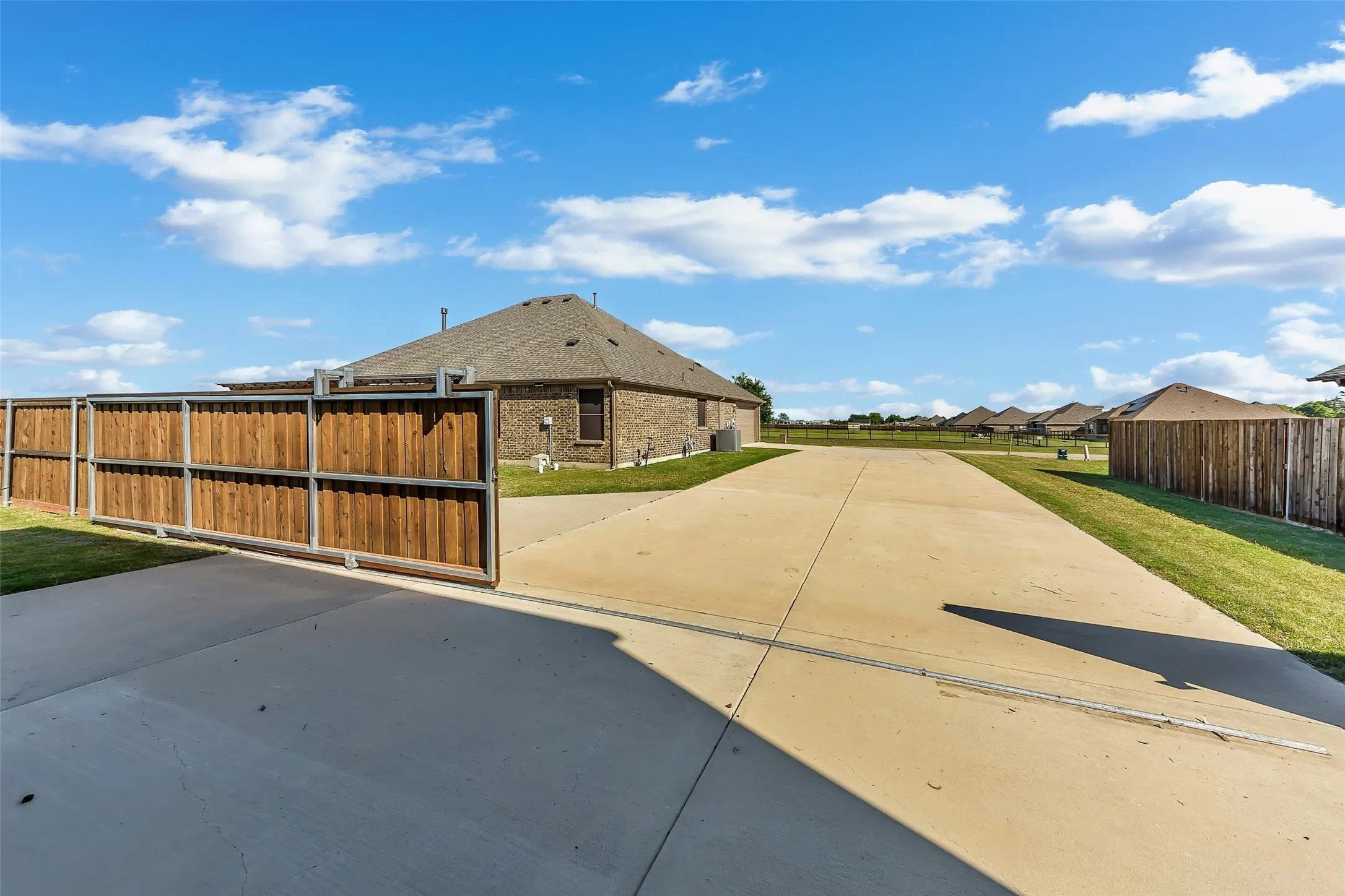 Long concrete driveway with a sliding wood-panel gate