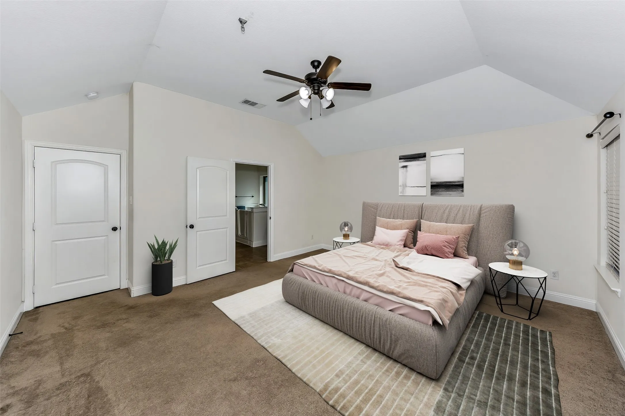Spacious room featuring vaulted ceilings, ceiling fan, carpet flooring, a window with blinds, and white interior doors with black hardware