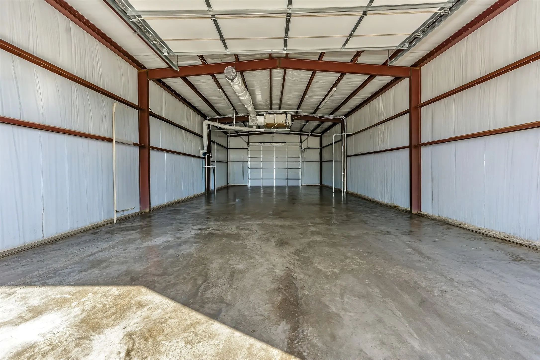Expansive clear-span commercial interior featuring a concrete floor, exposed steel framing, and corrugated metal walls