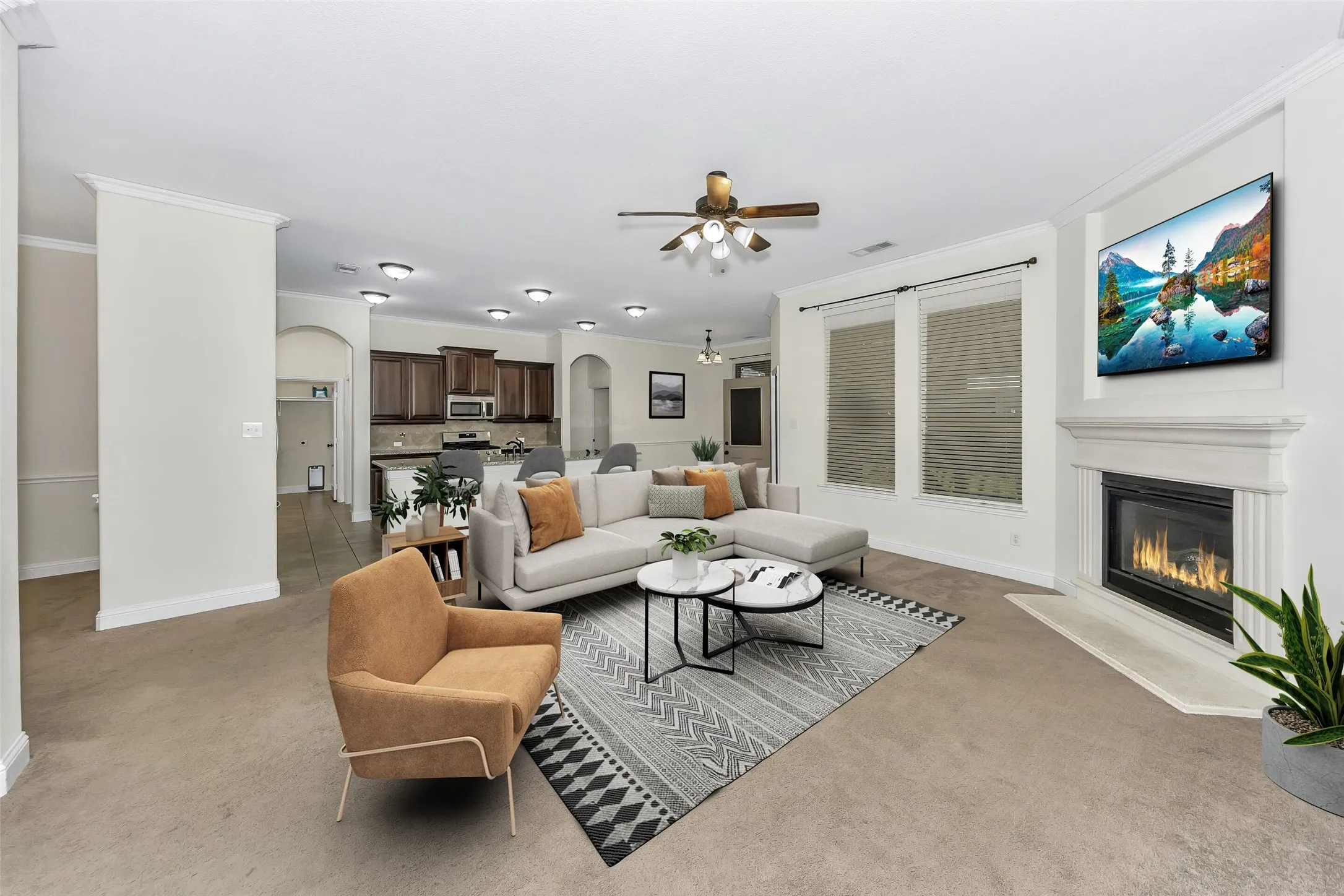 Spacious living area featuring a fireplace with a white mantel, dual windows with blinds, a ceiling fan, recessed lighting, and crown molding