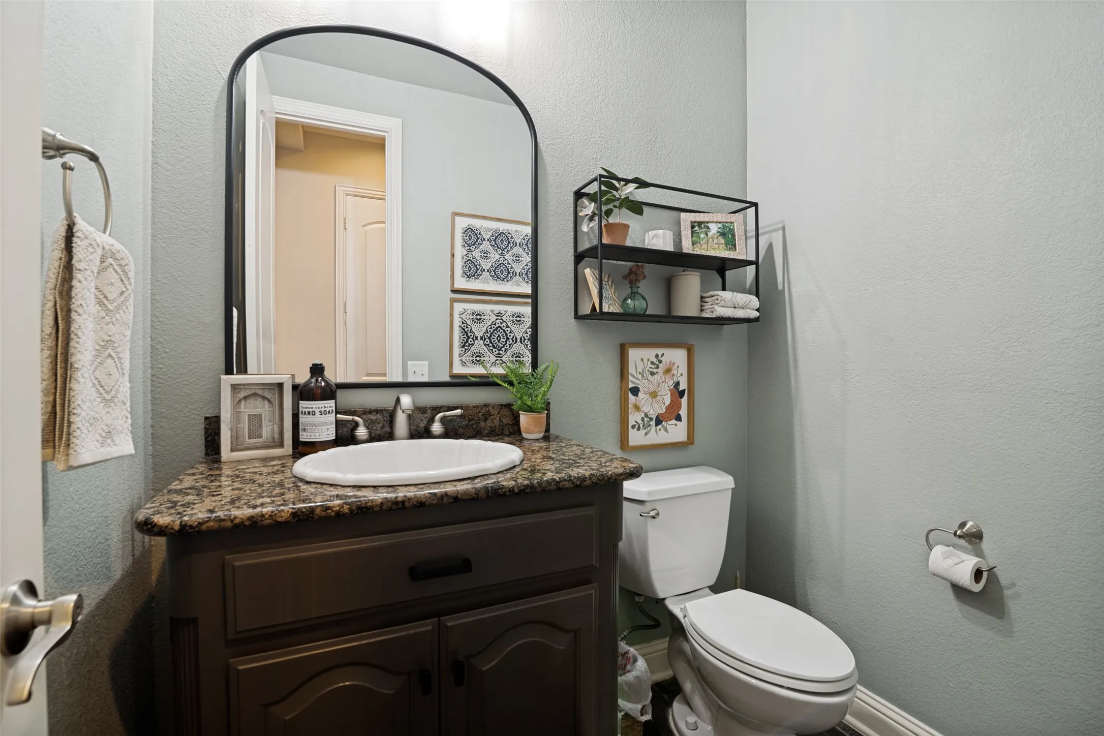 Bathroom vanity featuring a granite countertop, white oval sink, and dark wood-finish cabinetry