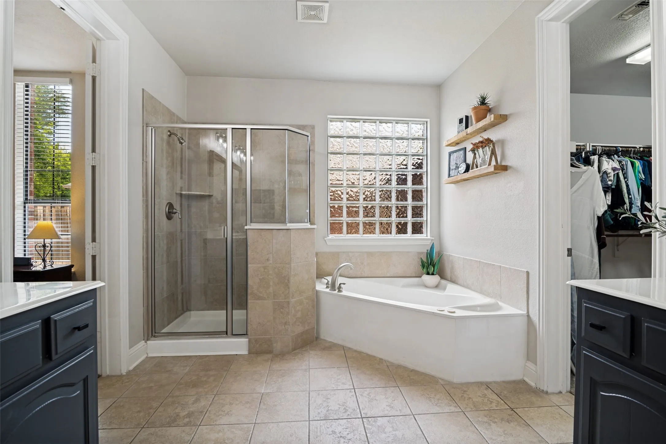 Bathroom featuring a corner soaking tub, a glass-enclosed shower, and a glass block window