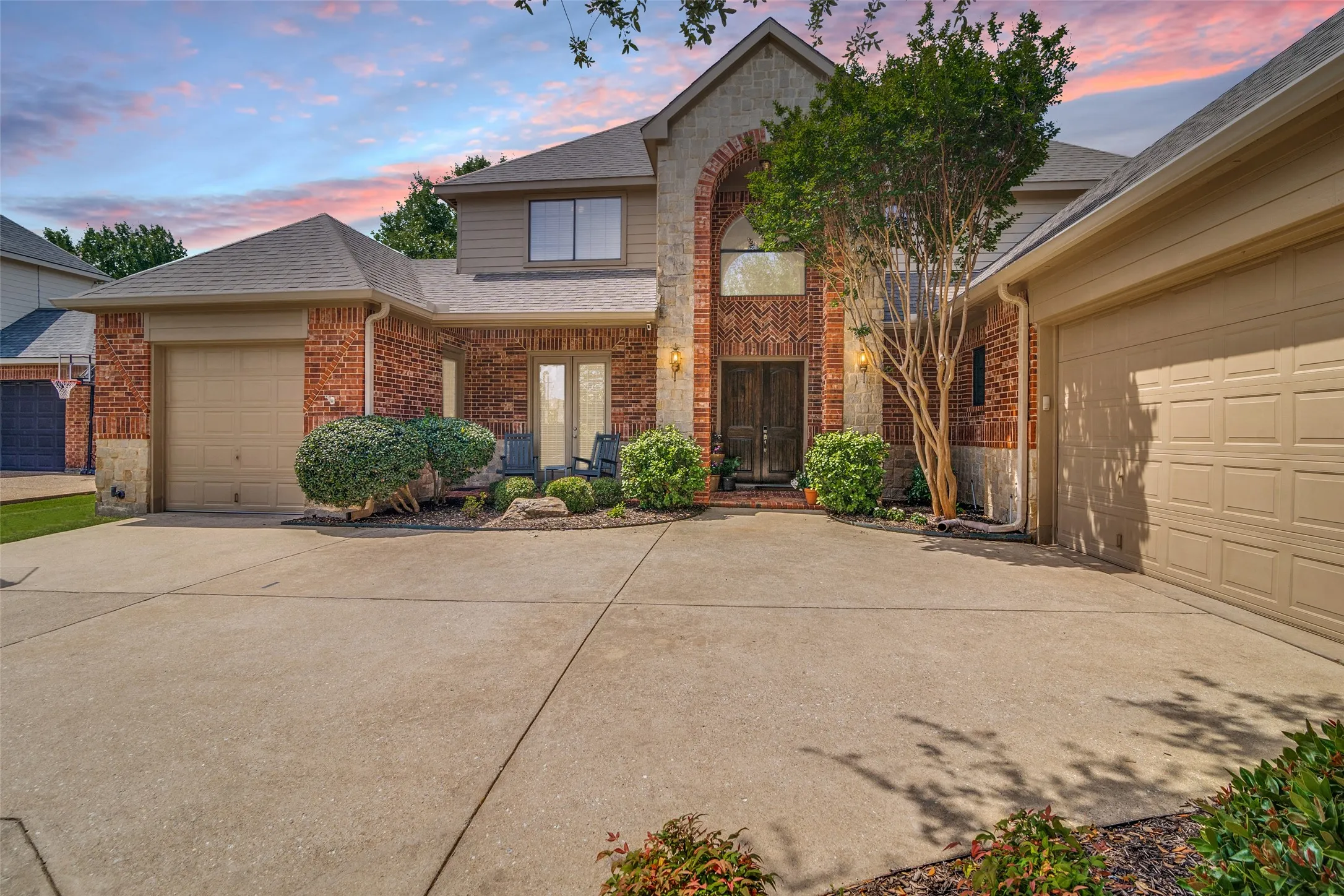 Brick exterior with stone accents, arched entryway, double-door entry, and two attached garages