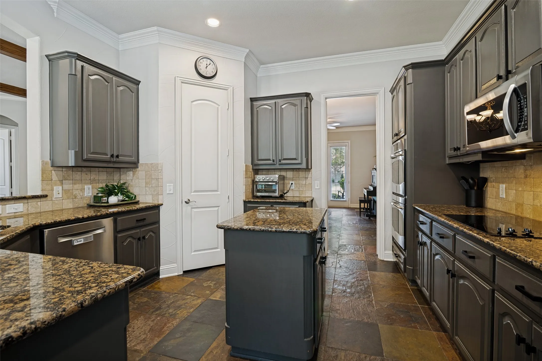 Kitchen featuring dark wood-finish cabinetry, granite countertops, and stone tile flooring