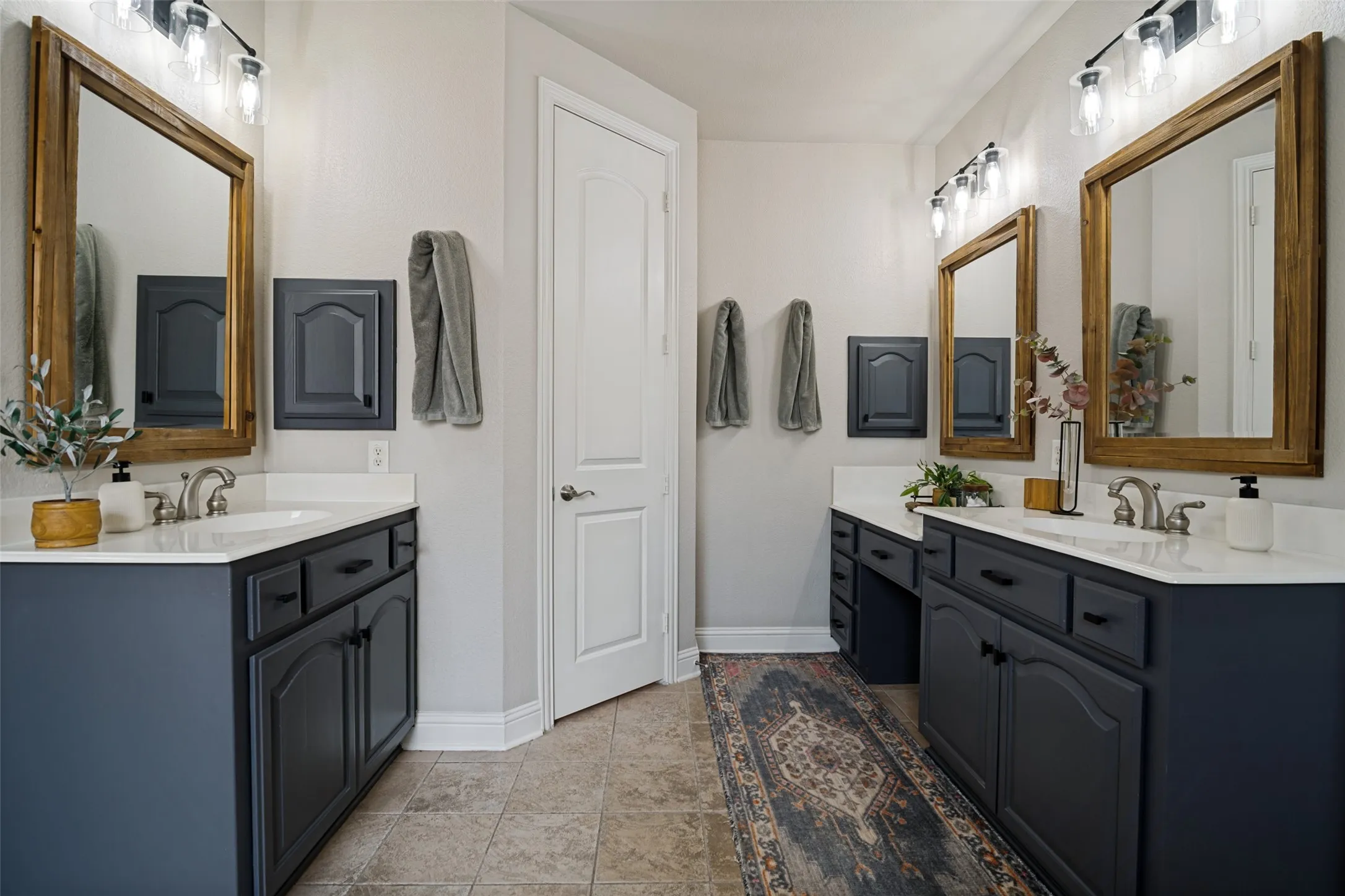 Dual vanity bathroom featuring stone countertops, dark cabinetry, and individual framed mirrors with overhead lighting
